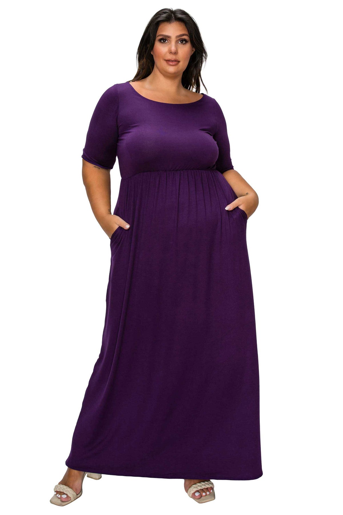 A woman modeling a long, short-sleeved purple maxi dress with side pockets, shown against a plain white background.