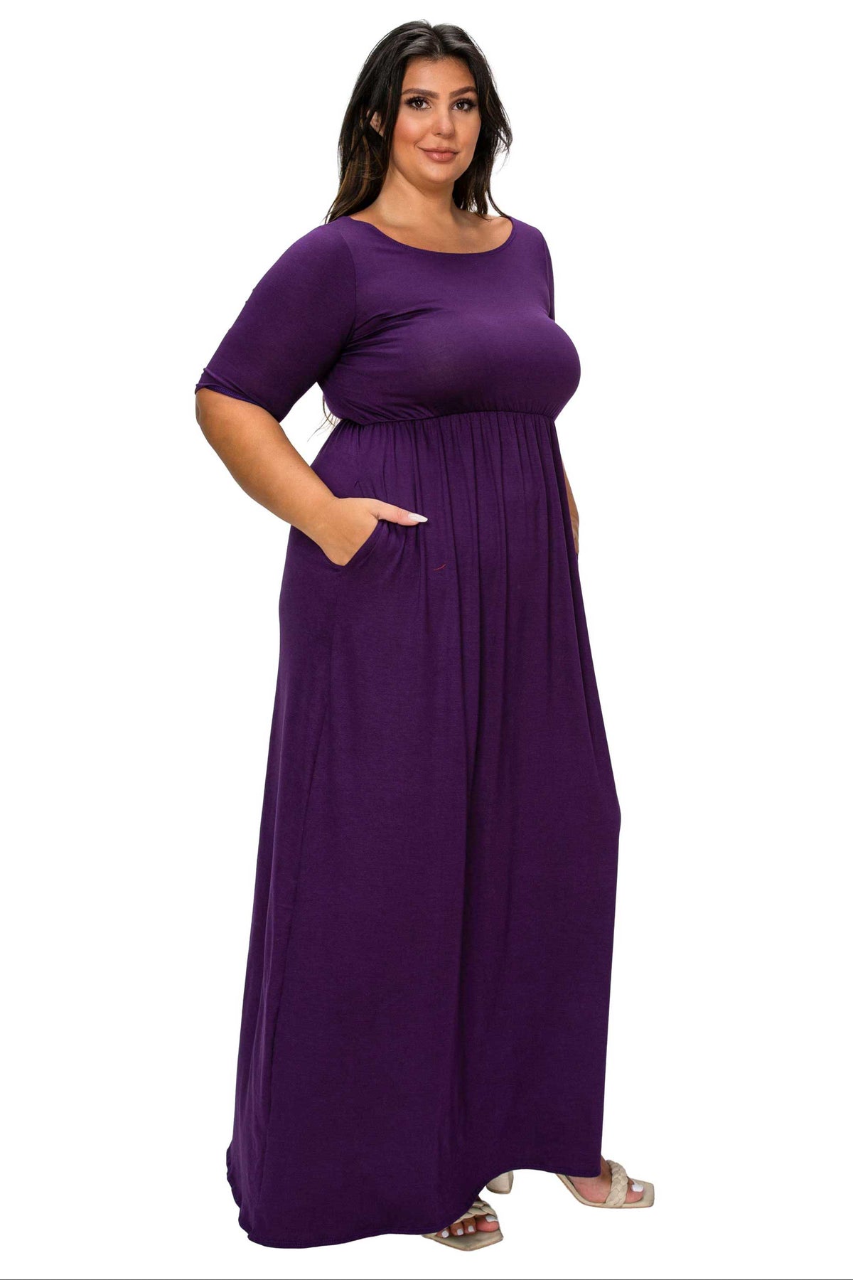 A woman modeling a purple maxi dress with short sleeves, a scoop neckline, and side pockets against a plain white background.