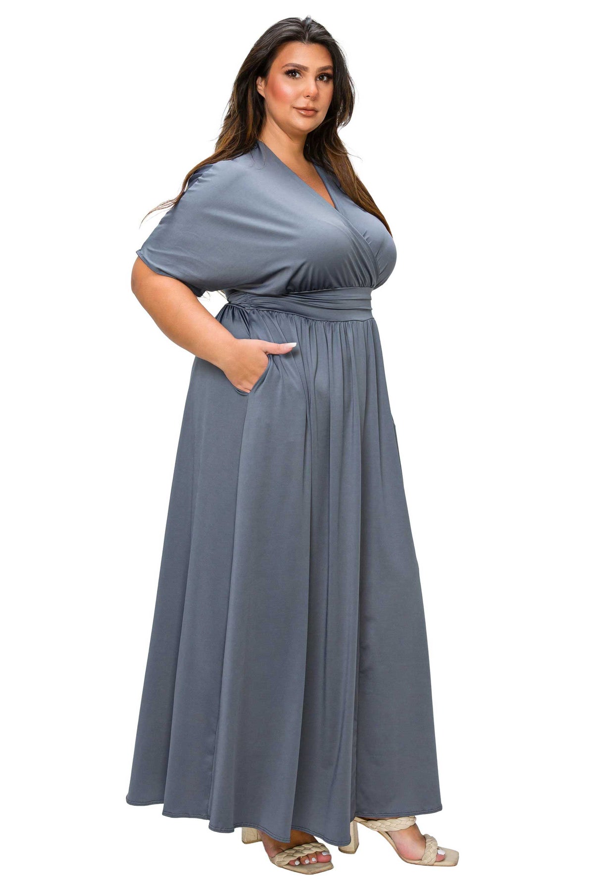 A woman modeling a floor-length, short-sleeve wrap-style dress in a muted slate blue-gray color, shown against a plain white background.