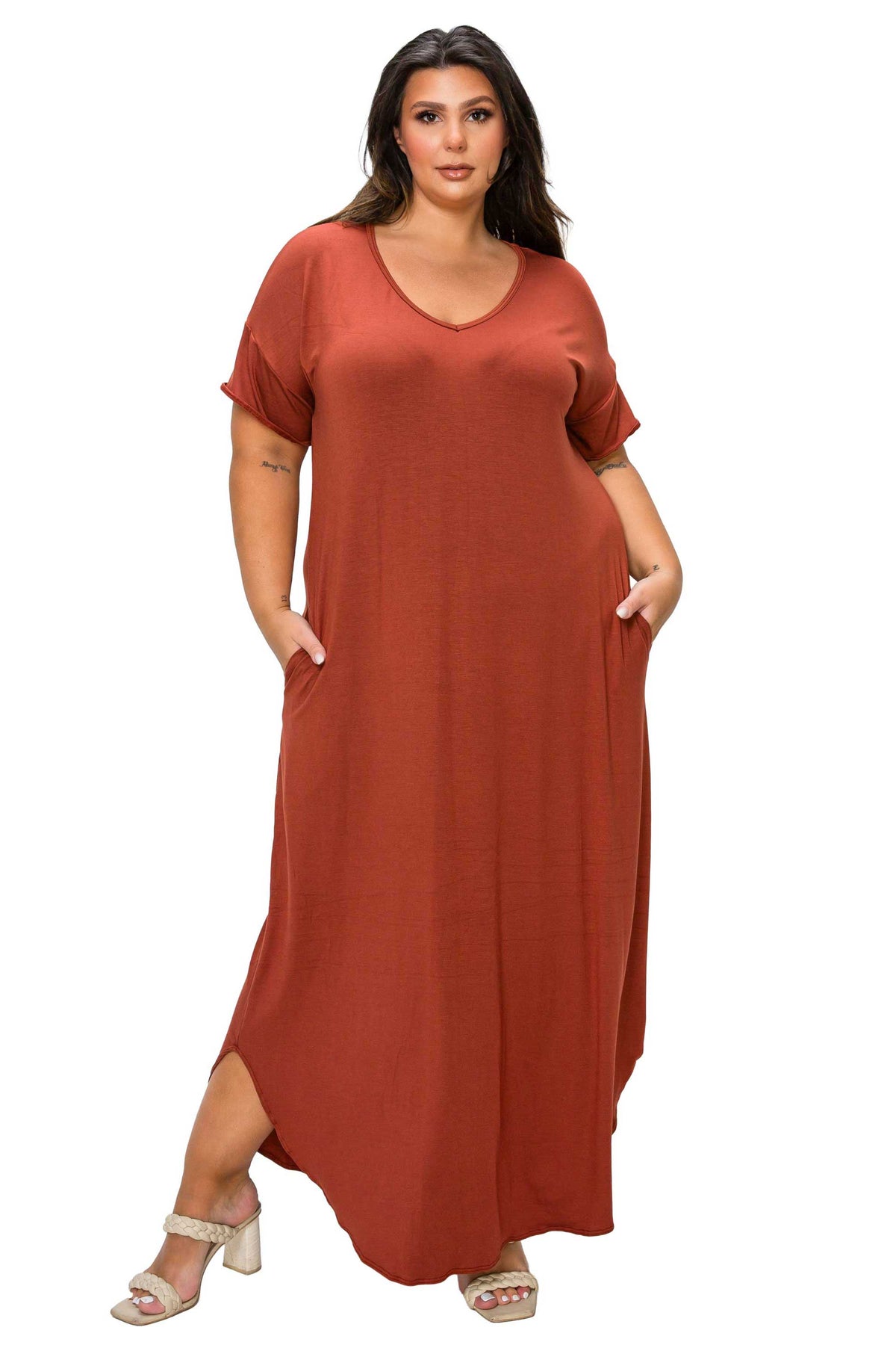 A woman modeling a rust-colored, short-sleeved maxi dress with a V-neckline and side pockets, paired with beige heeled sandals, set against a plain white background.