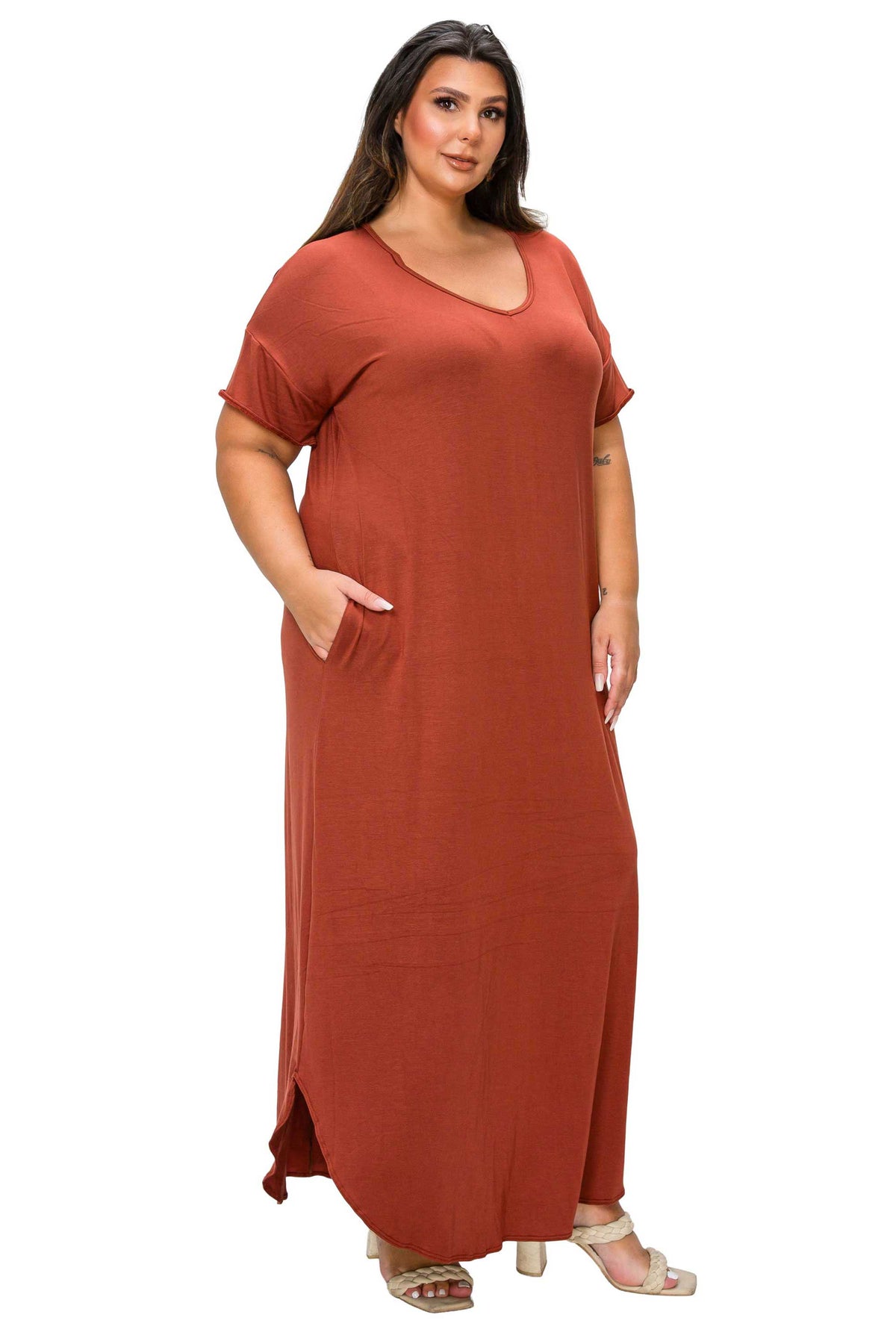 A woman modeling a rust-colored, short-sleeve maxi dress with side pockets against a plain white background.
