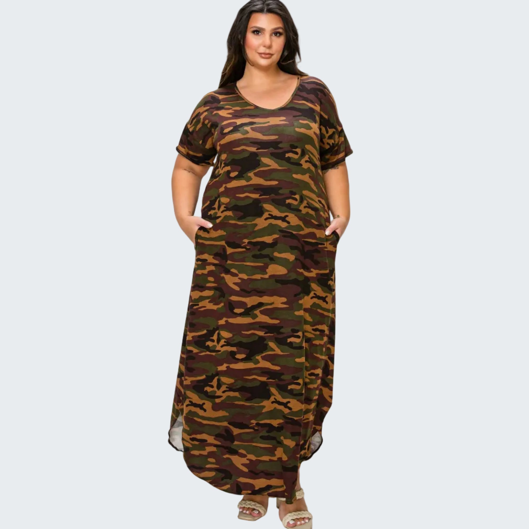 A woman modeling a long-sleeve, floor-length camouflage maxi dress with side pockets, shown against a plain white background.