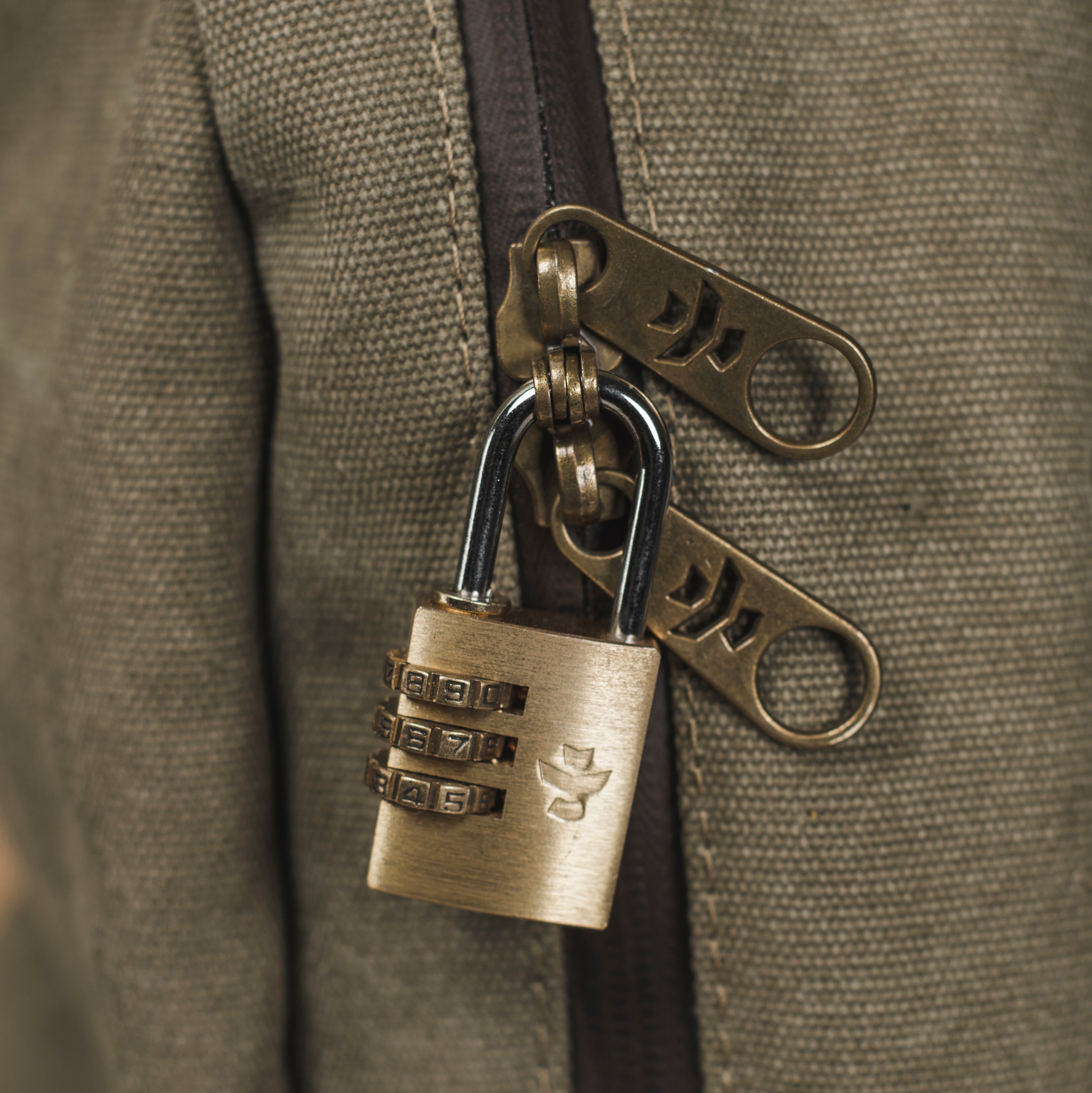 Bronze combination lock keychain attached to a textured surface