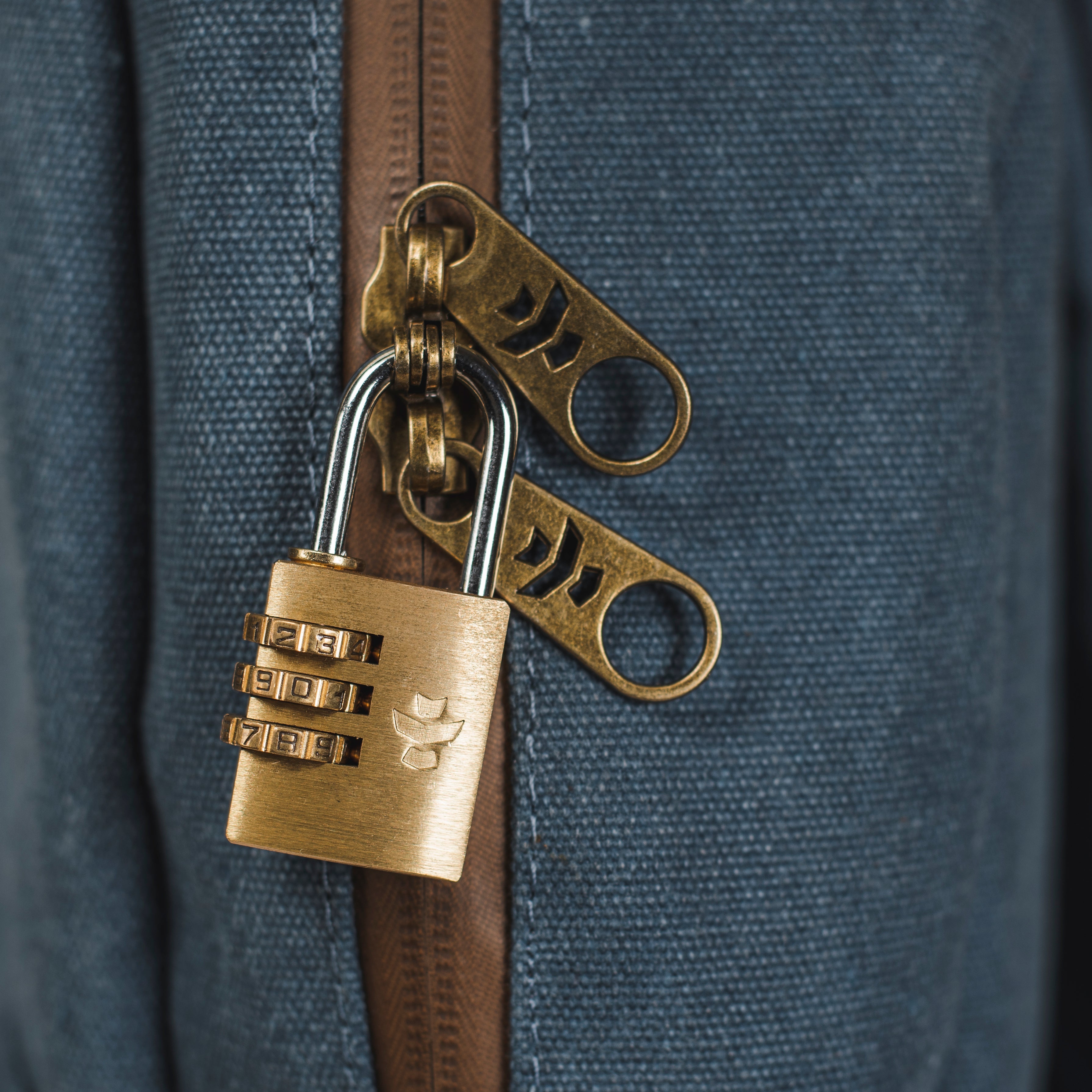 Brass padlock with keychain attached to a blue bag