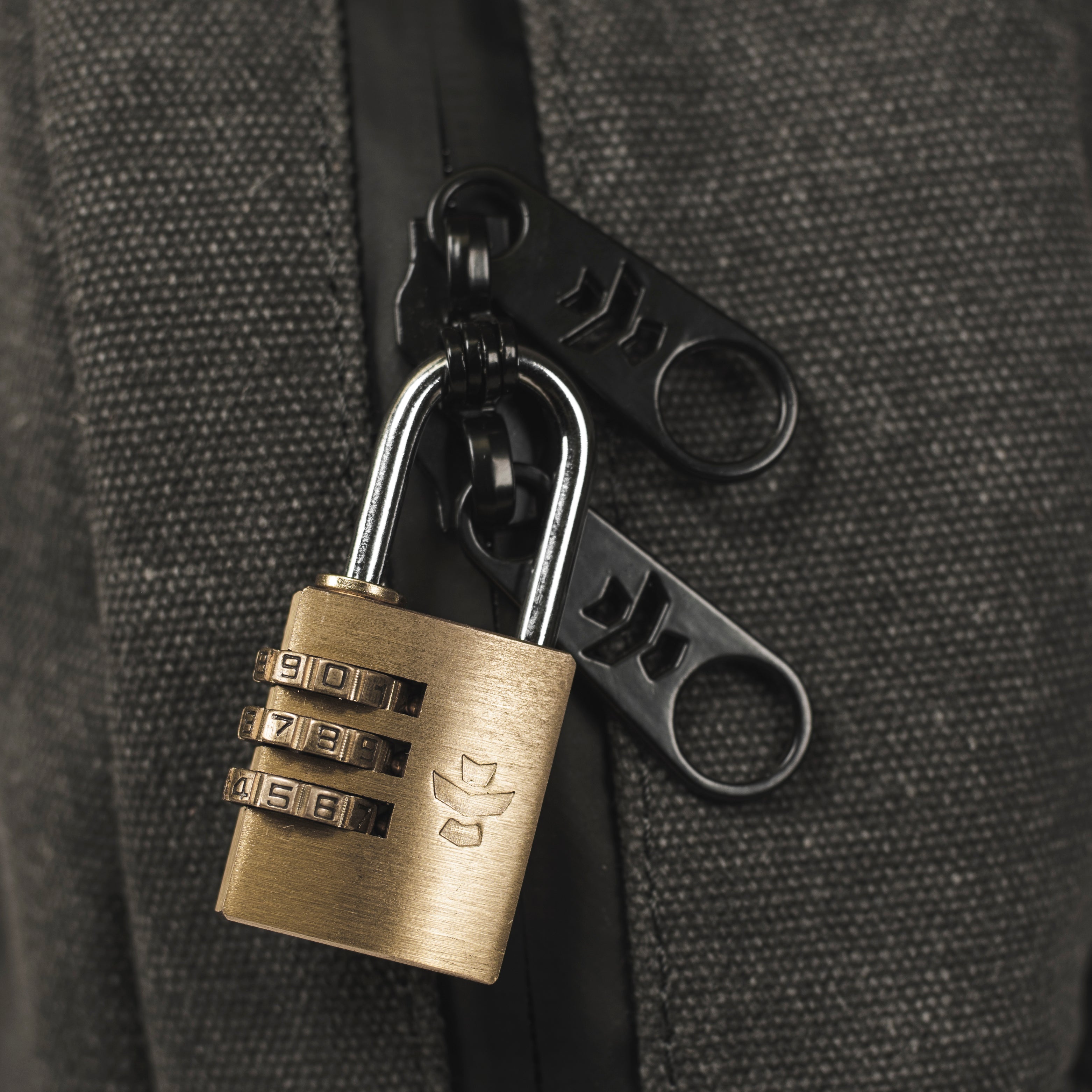 Brass combination lock attached to a black bag