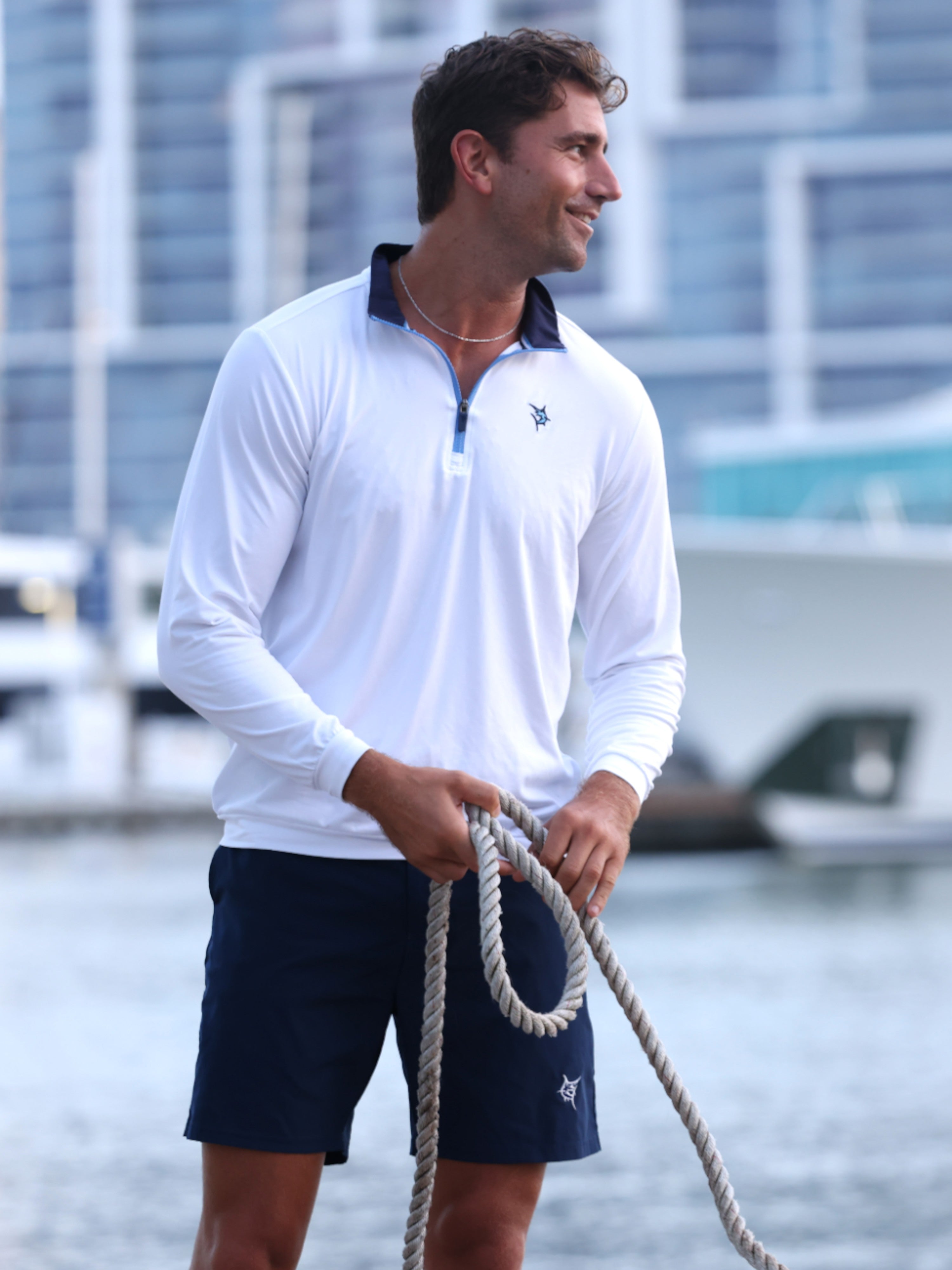 Man holding a rope by a waterfront with a blurred background