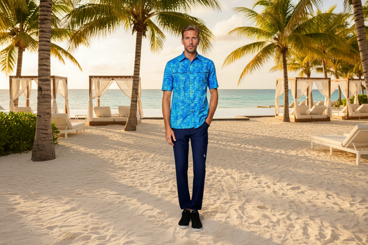 Man wearing a blue patterned shirt and dark pants on a white background