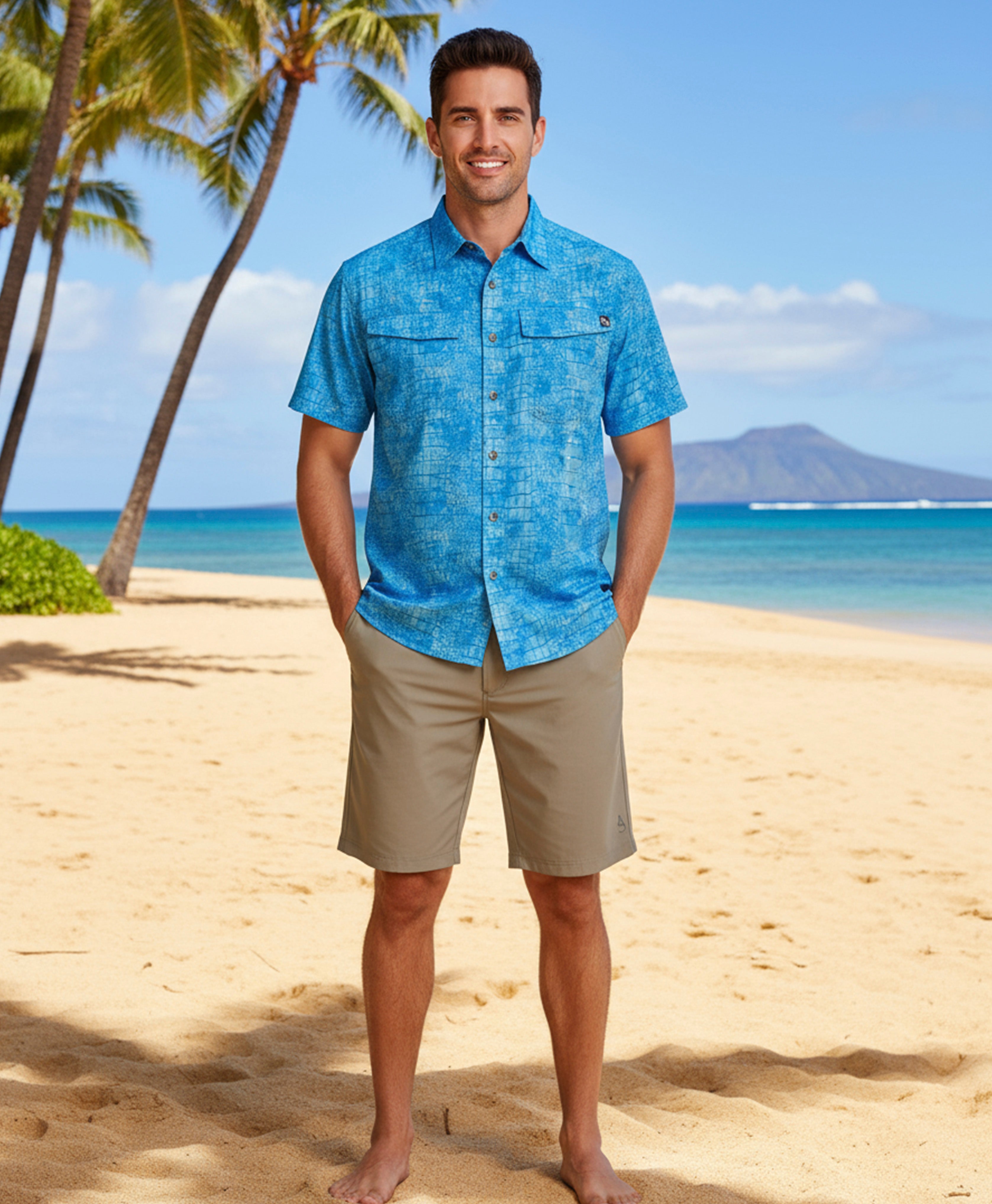 Man in a blue shirt and beige shorts standing on a beach with palm trees and ocean in the background
