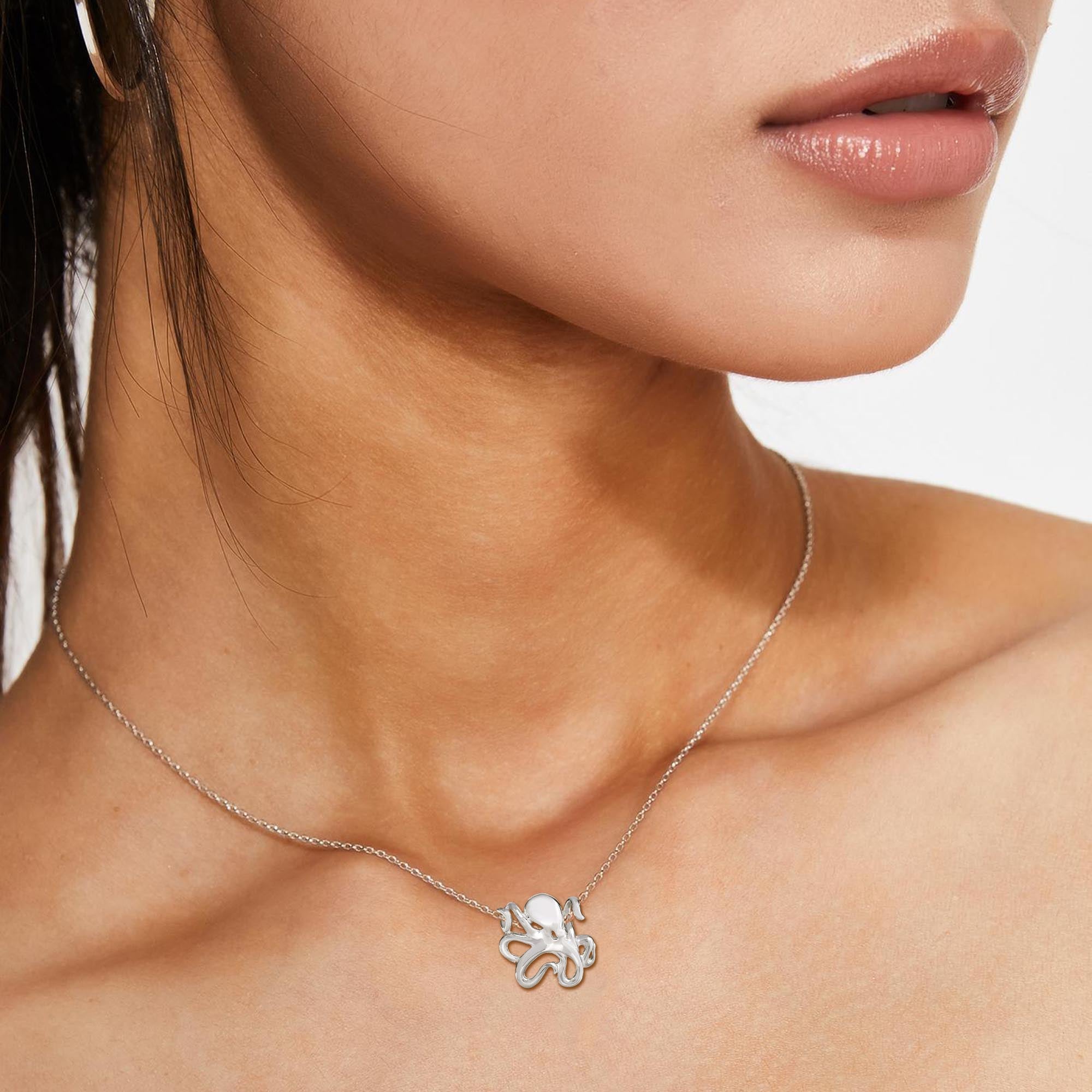 Silver necklace with a floral pendant worn by a person