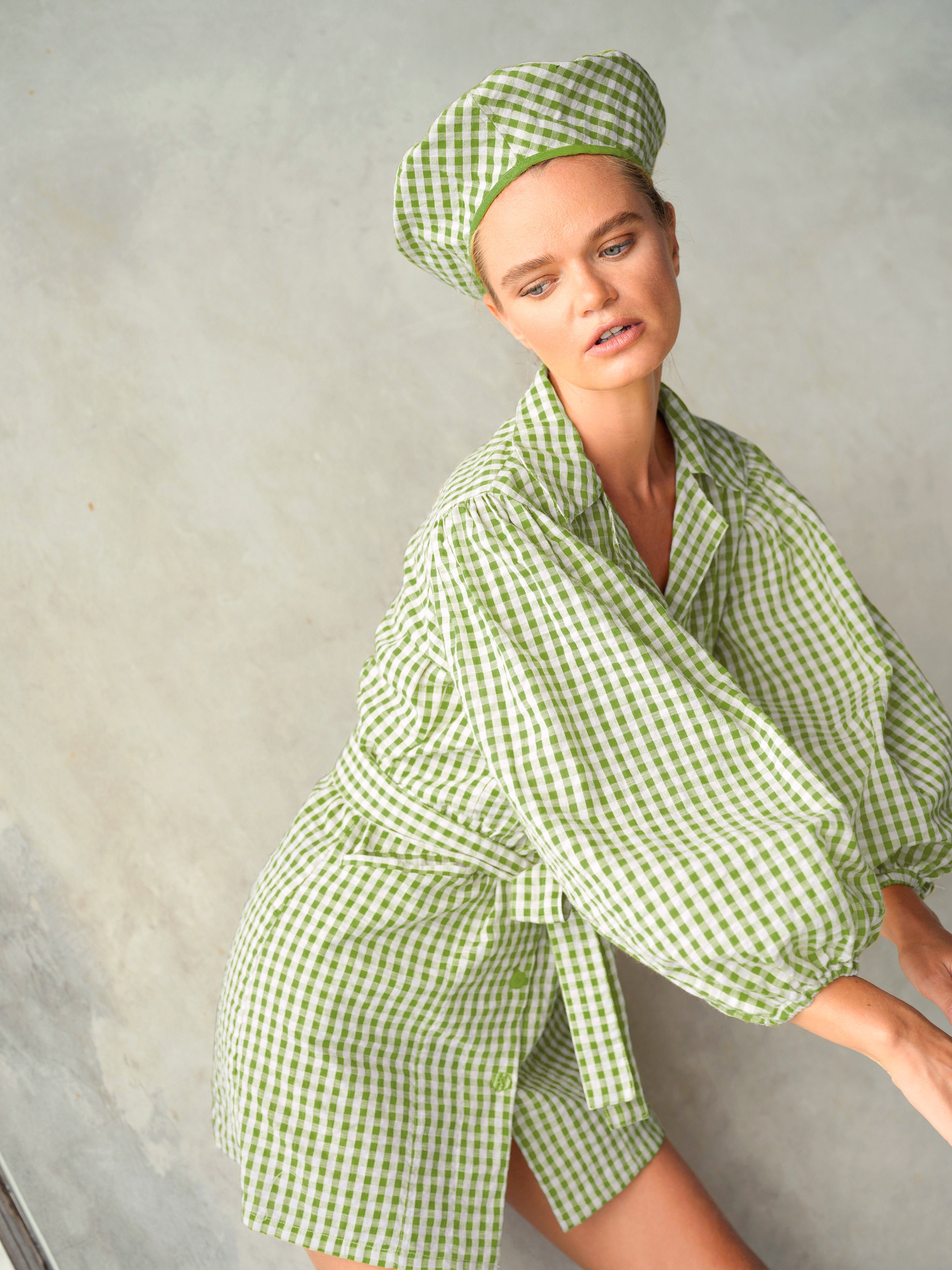 Woman wearing a green checkered robe and matching headband against a gray background