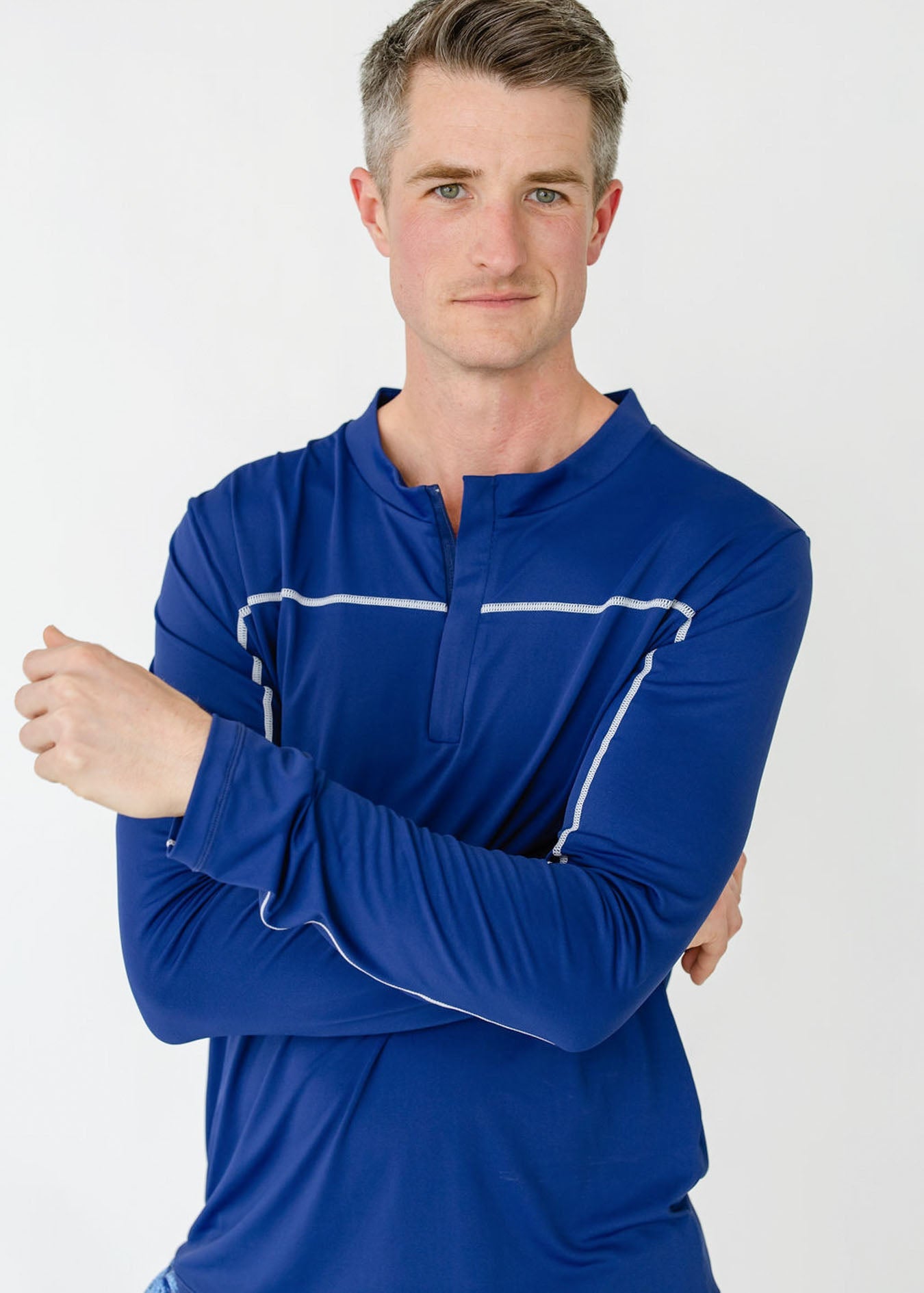 Man wearing a blue long-sleeve shirt with white accents on a white background