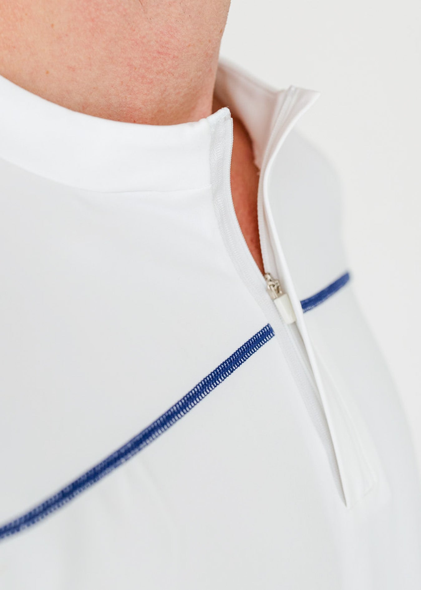 Close-up of a white jacket with blue zipper details on a white background