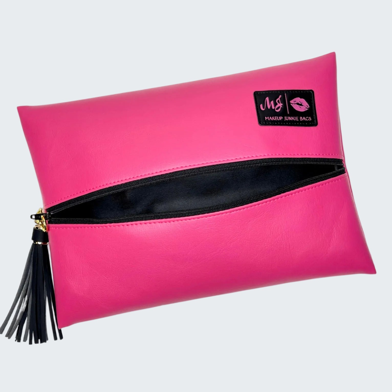 Pink clutch bag with black interior and tassel on a white background