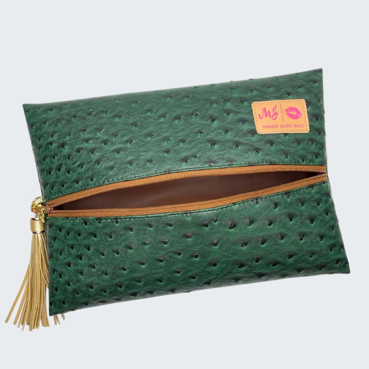 Green clutch bag with gold zipper and tassel on a white background
