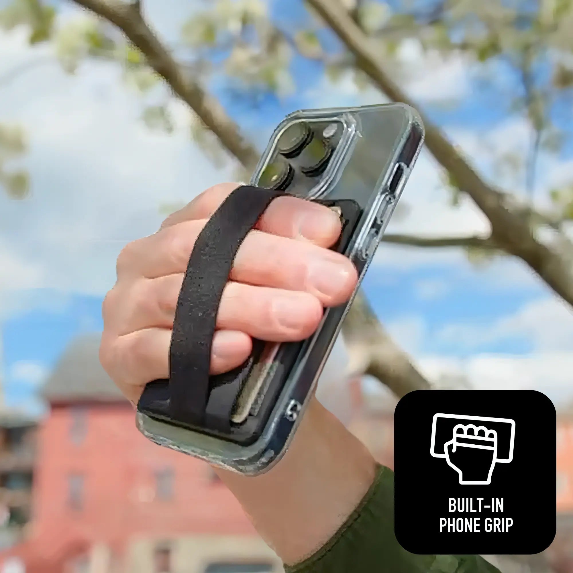 Hand holding a phone with a built-in phone grip against a blurred outdoor background