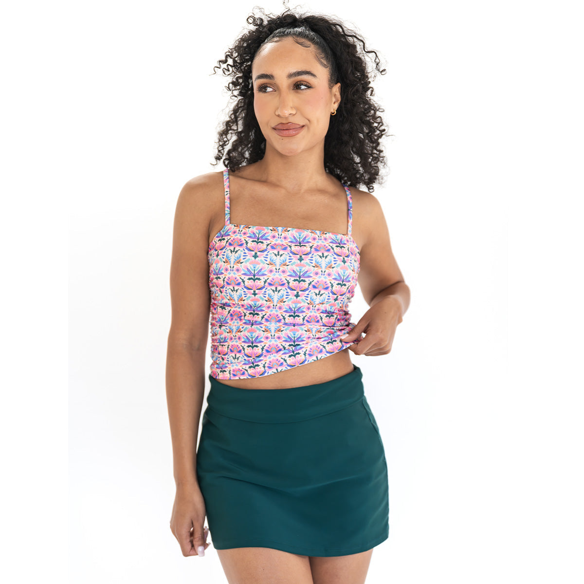 Woman wearing a floral top and green skirt on a white background