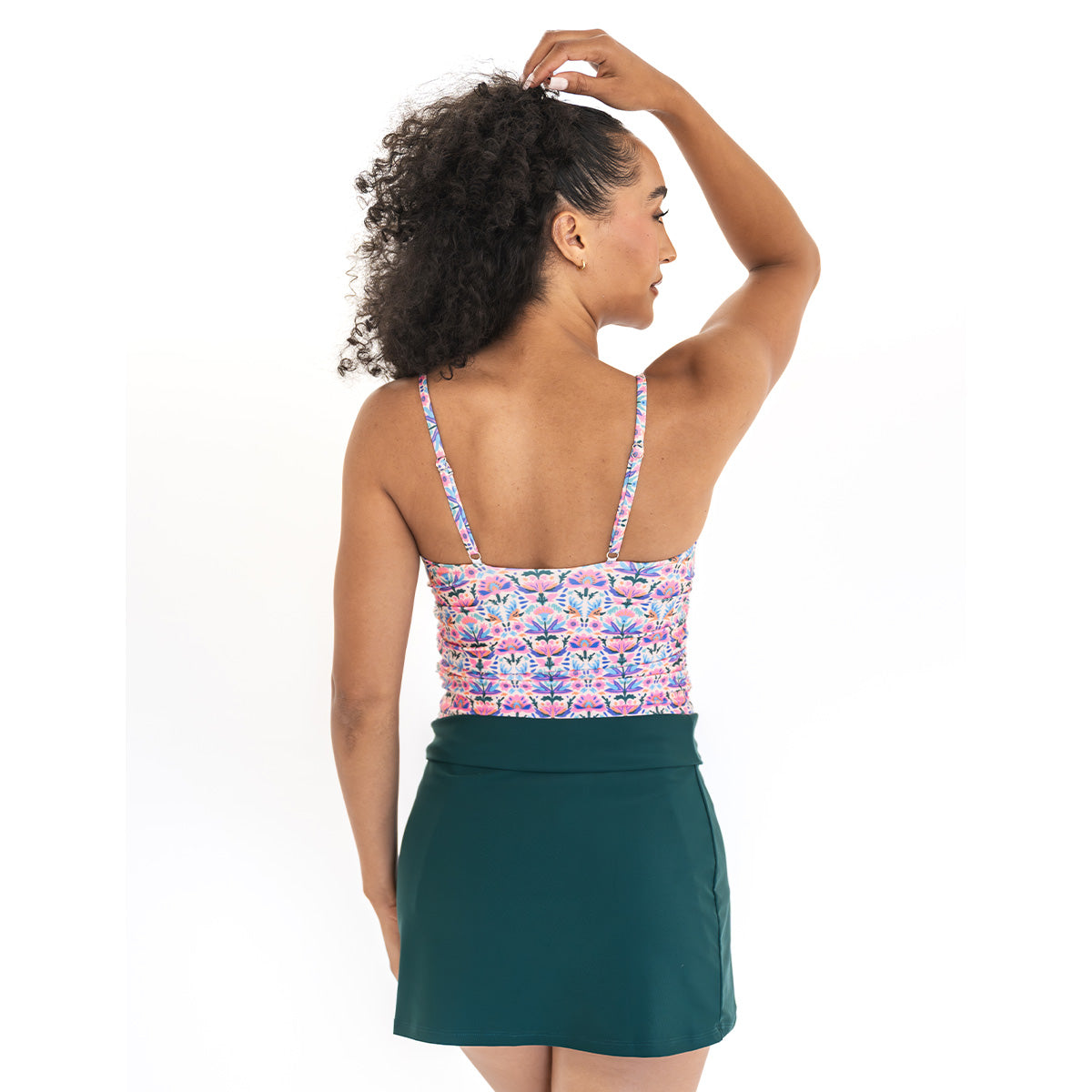 Woman wearing a floral top and green skirt on a white background
