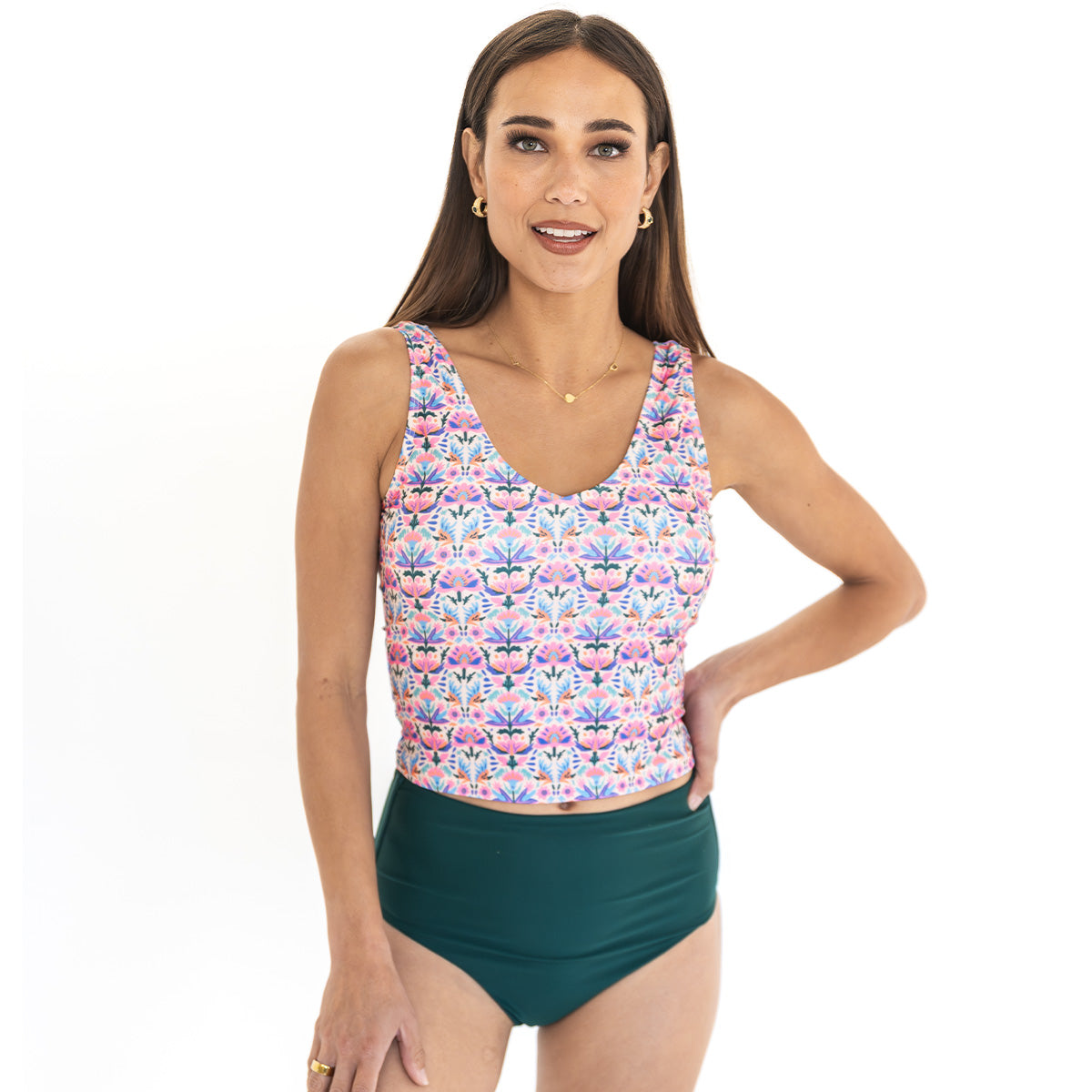 Woman wearing a colorful floral tankini top and green shorts on a white background