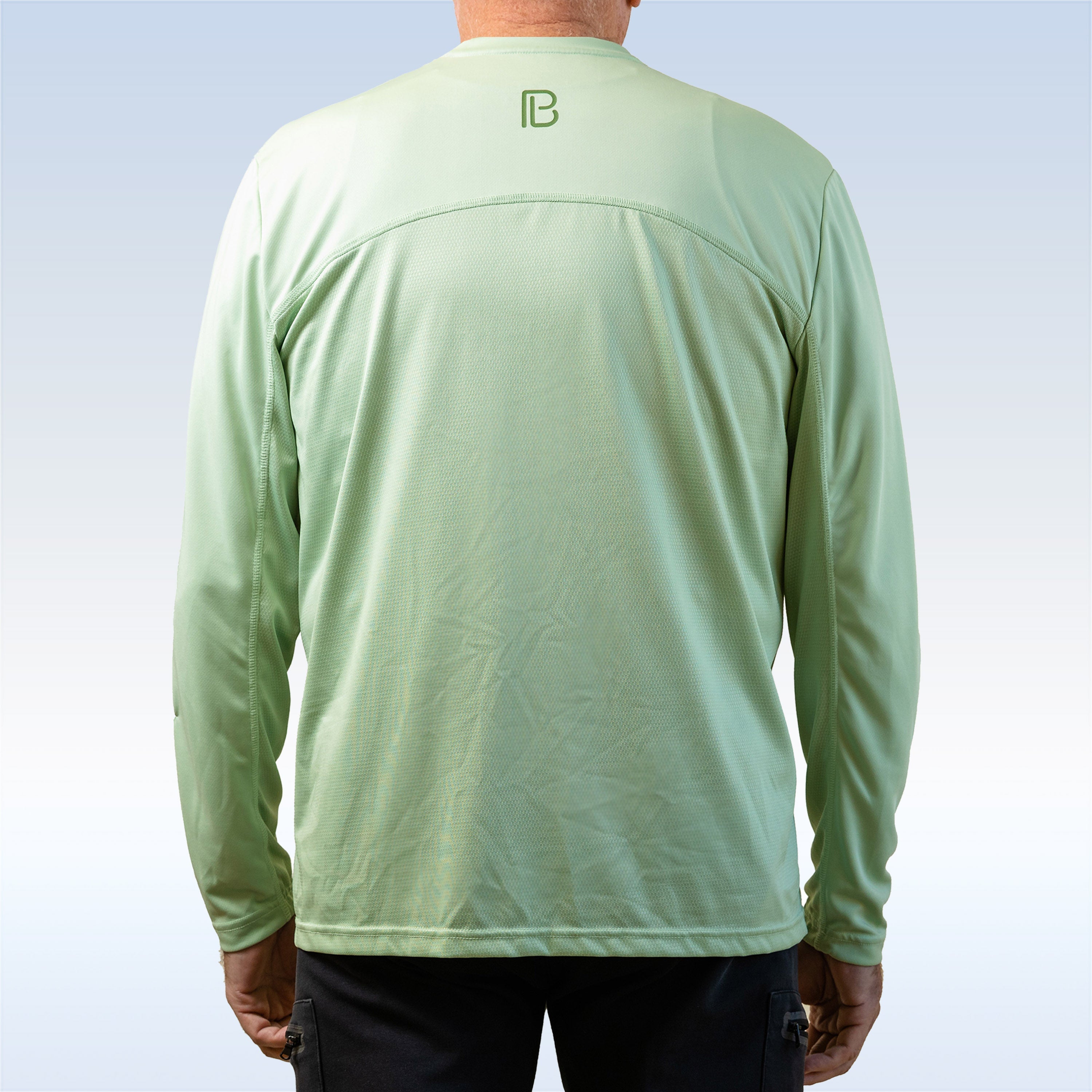 Person wearing a light green long-sleeve shirt with a logo on the back against a light blue background