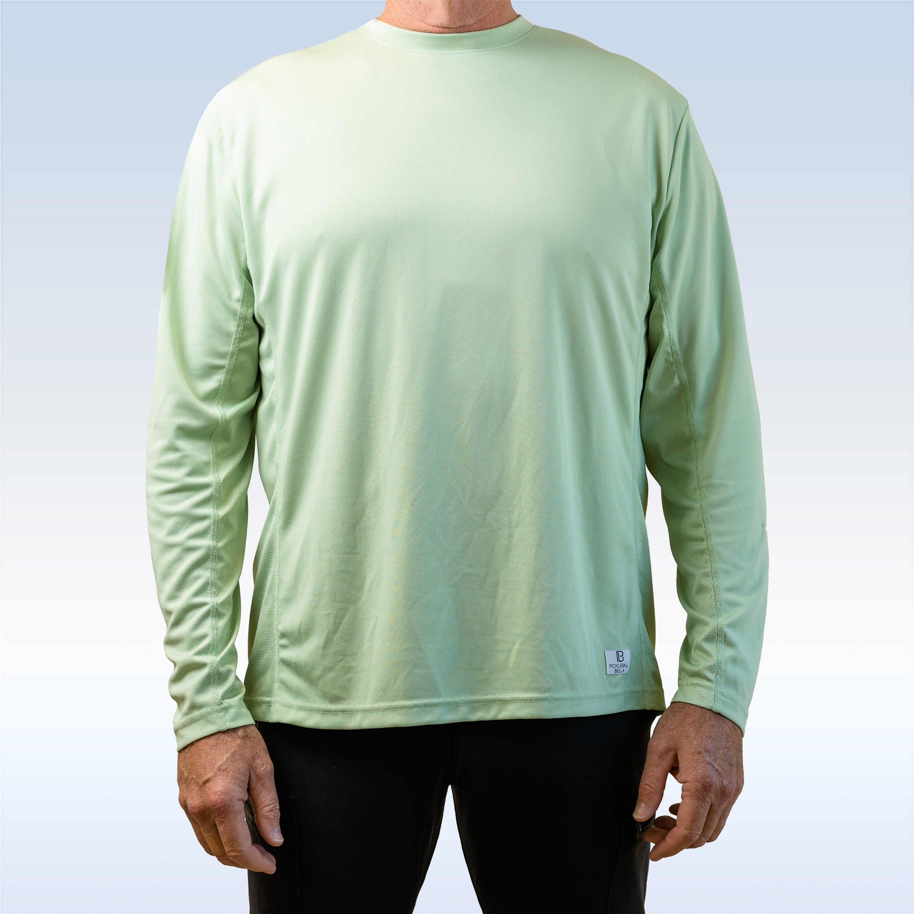 Person wearing a light green long-sleeve shirt with a brand logo on a light blue background
