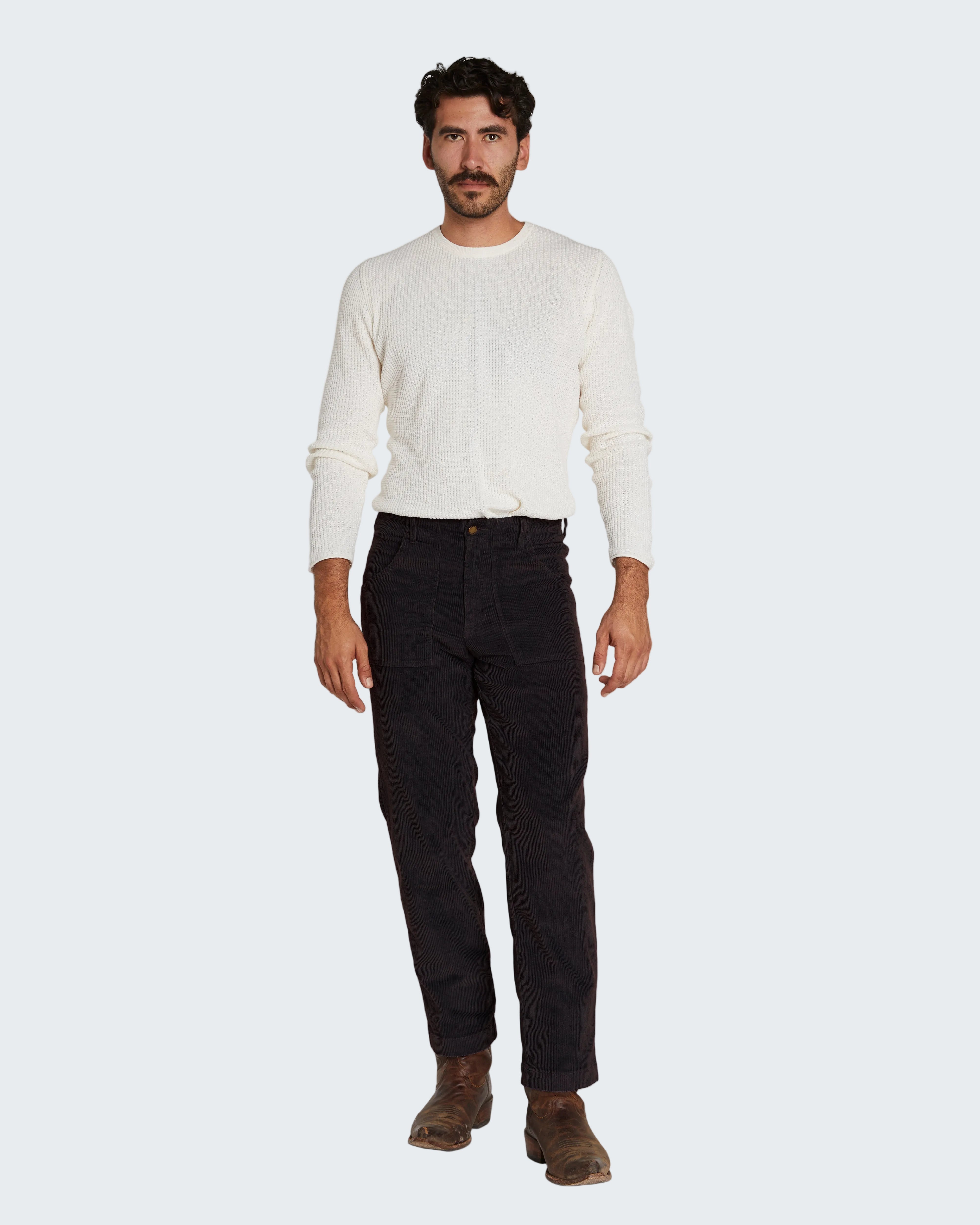 Man wearing a white sweater and dark pants on a white background