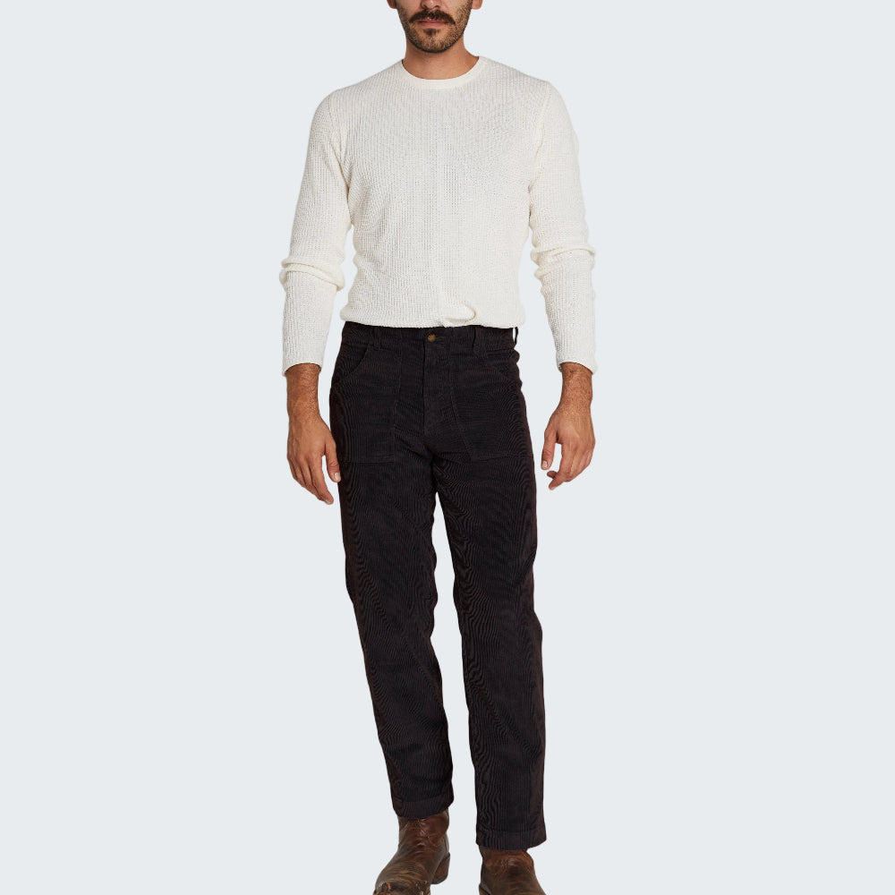 Man wearing a white sweater and dark pants on a white background