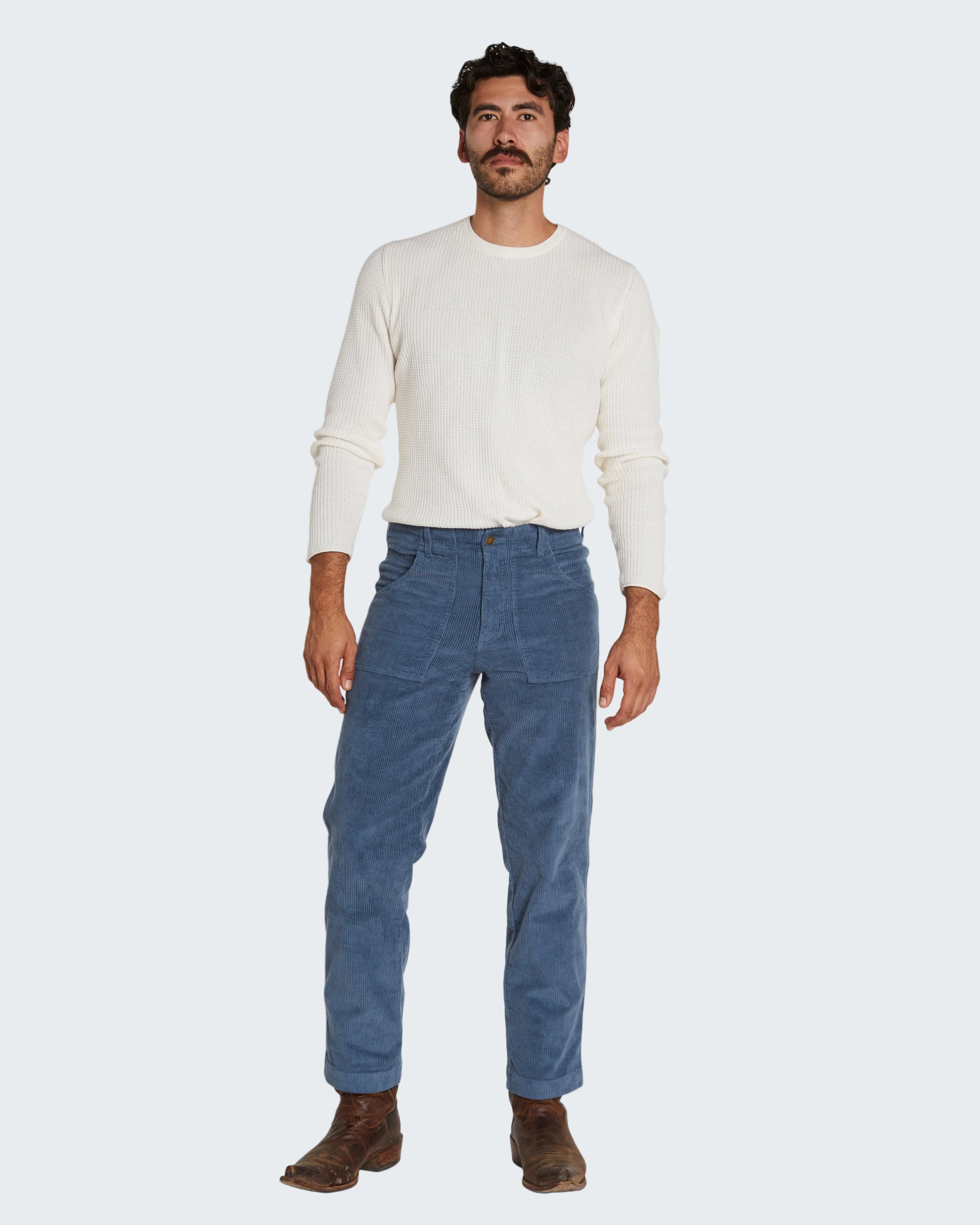 Man wearing a white sweater and blue pants on a white background