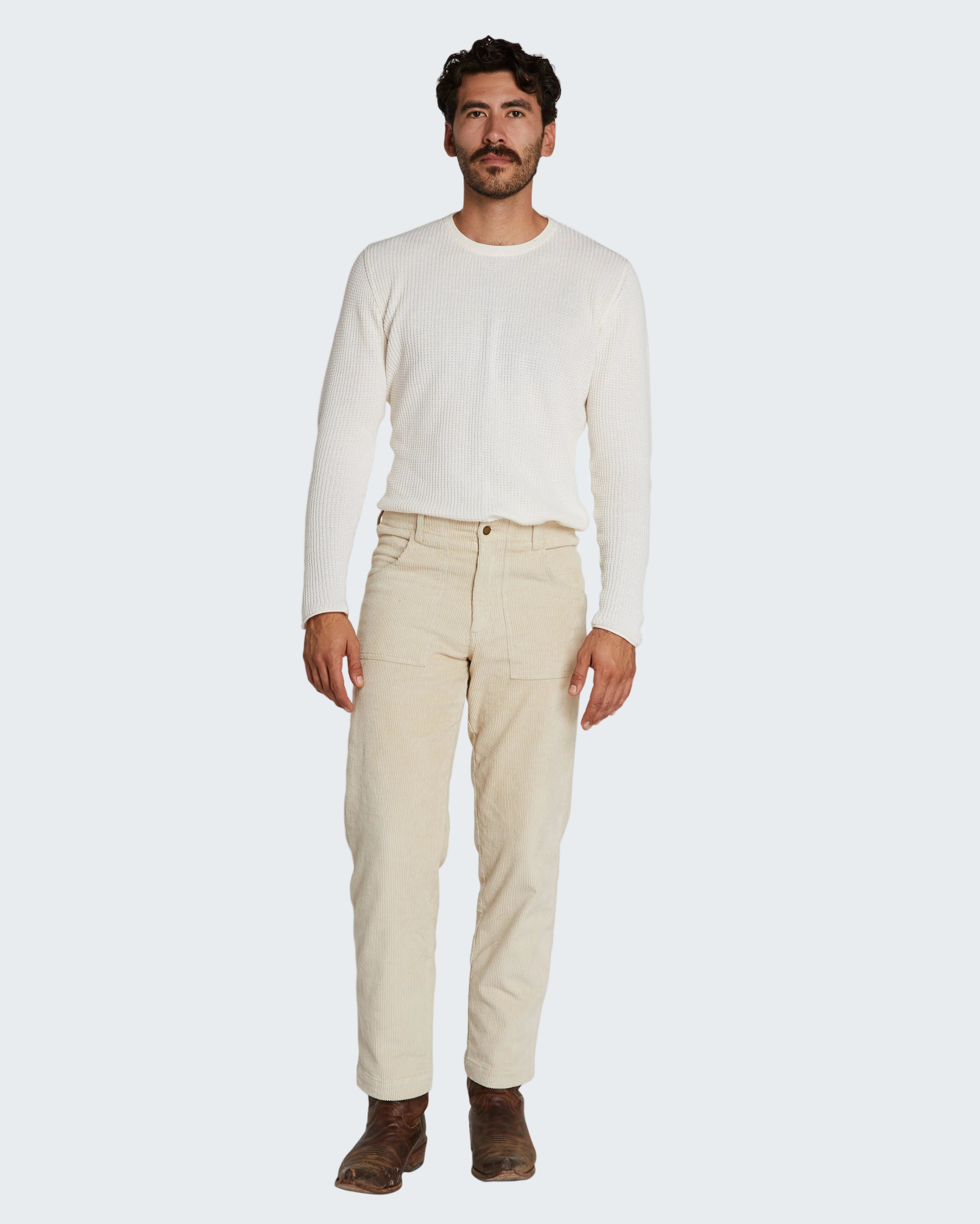 Man wearing a white long-sleeve shirt and beige pants on a white background