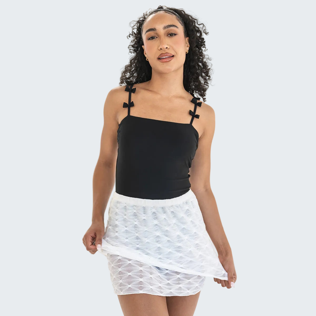 Woman wearing a black top and white skirt on a white background