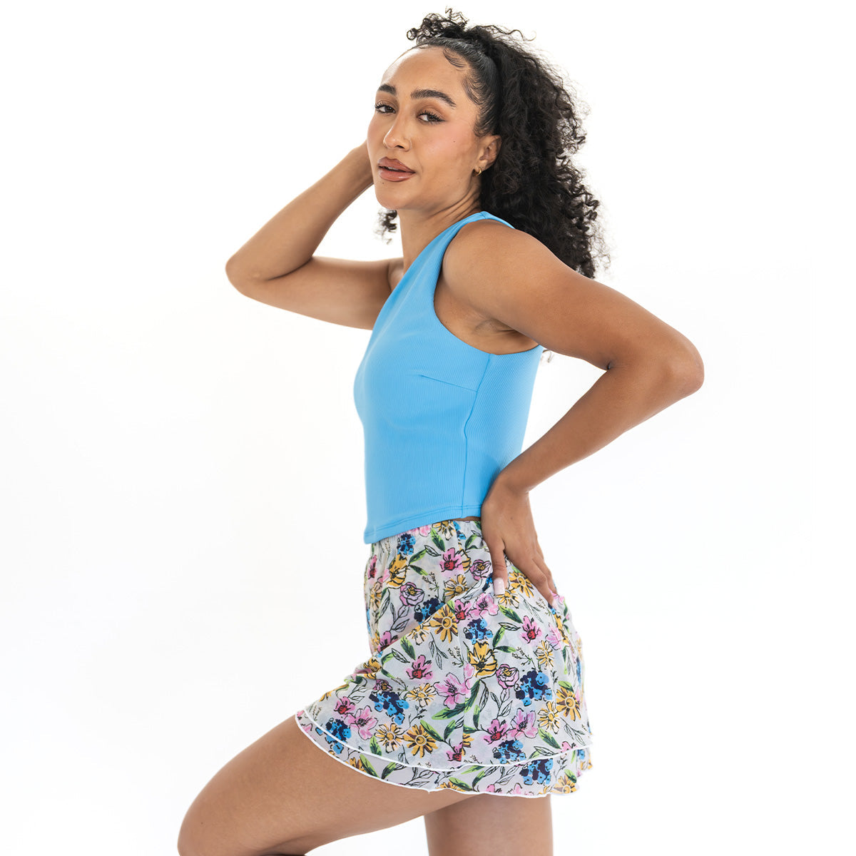 Woman wearing a blue tank top and floral skirt on a white background