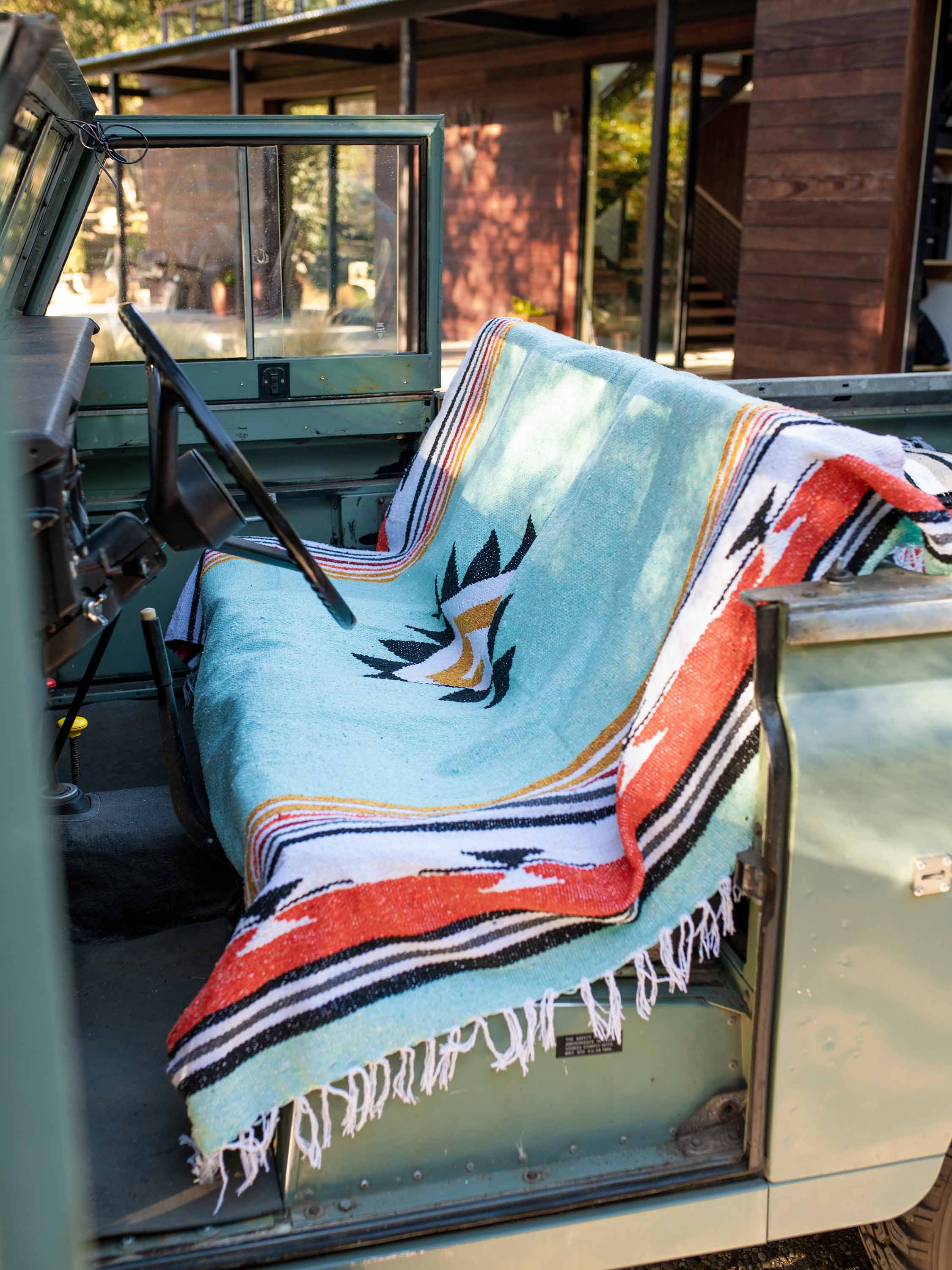 Colorful blanket with Native American design draped over a vehicle's open door.