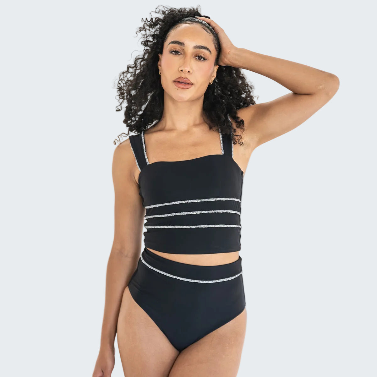 Woman wearing a black bikini with white stripes on a white background