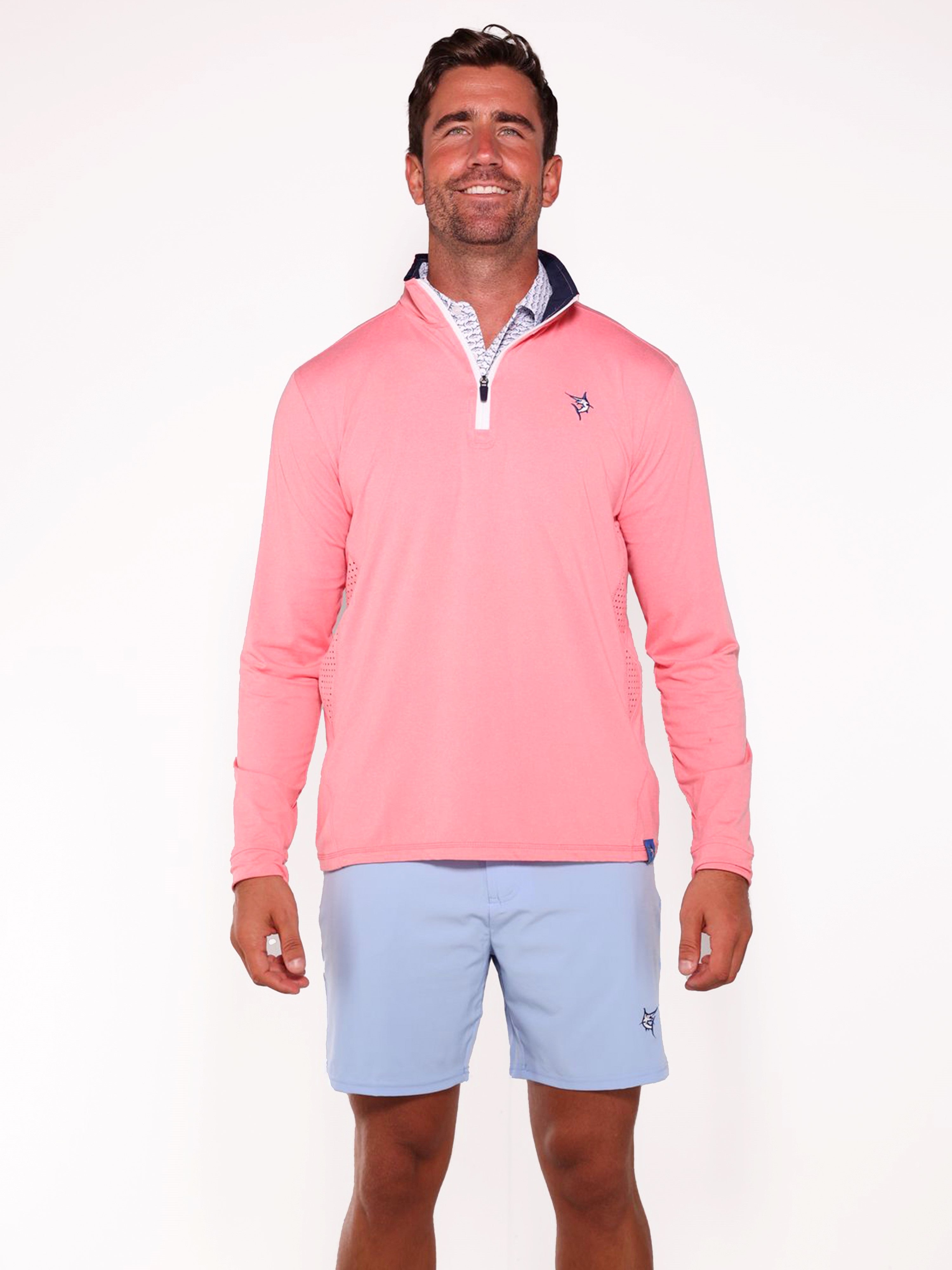 Man wearing a pink long-sleeve shirt and light blue shorts on a white background
