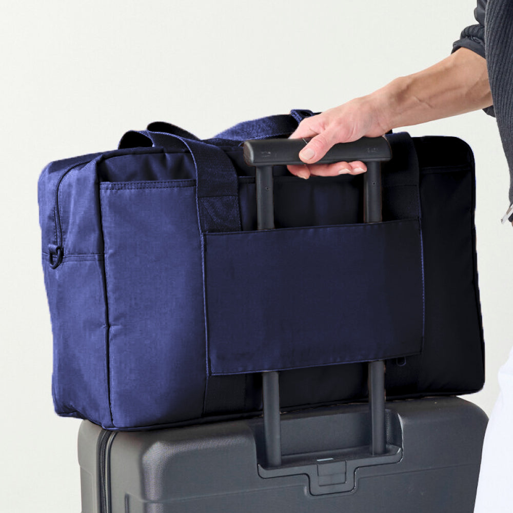 Person holding a navy blue bag over a gray suitcase on a white background