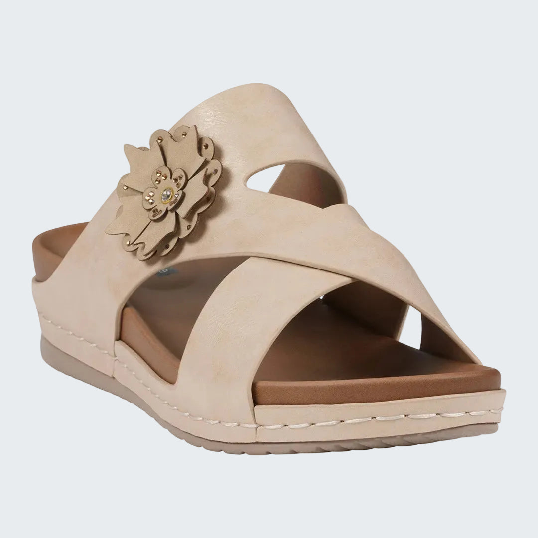 Beige sandal with a decorative flower on a white background