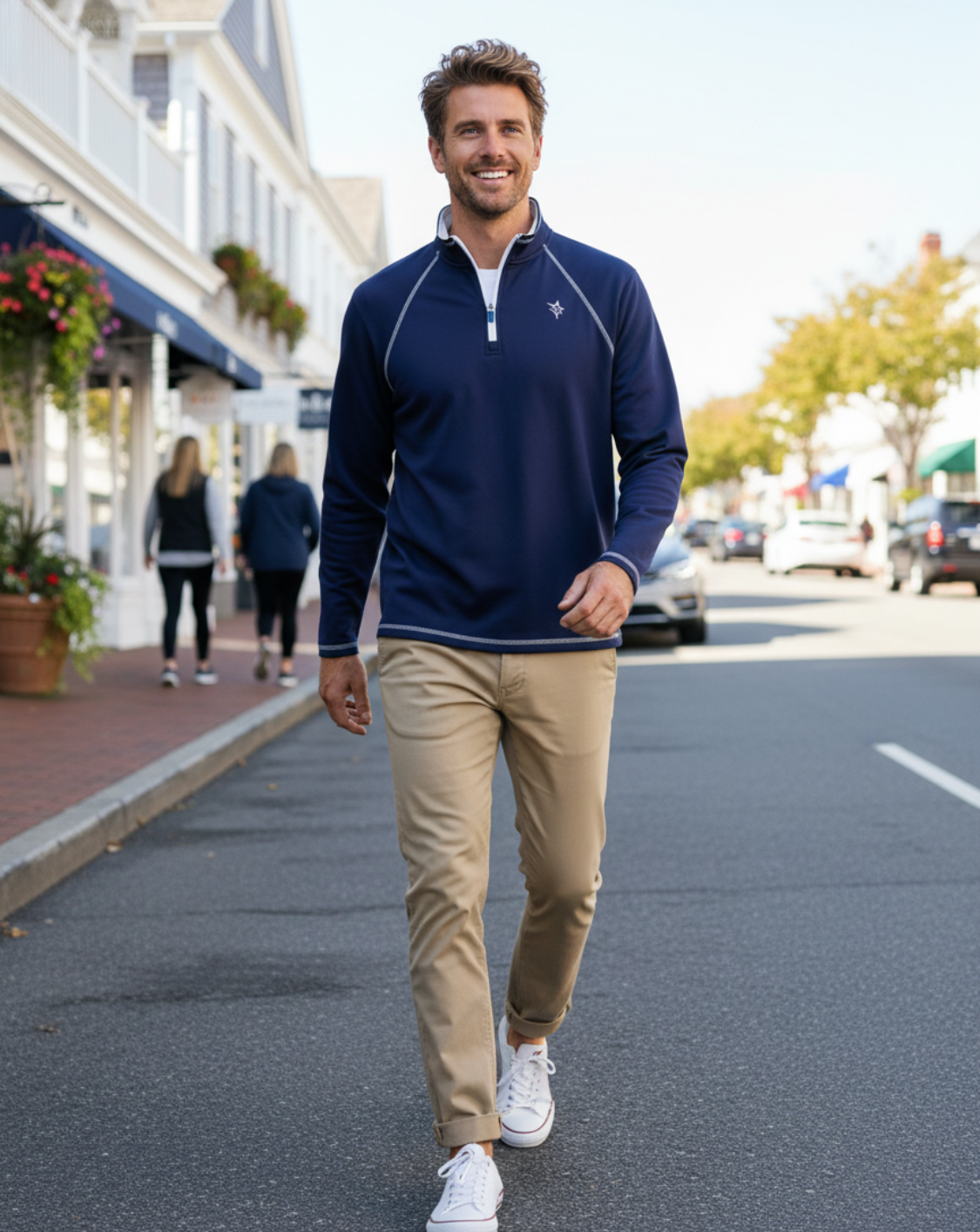 Man walking on a street wearing a navy long-sleeve shirt and beige pants.