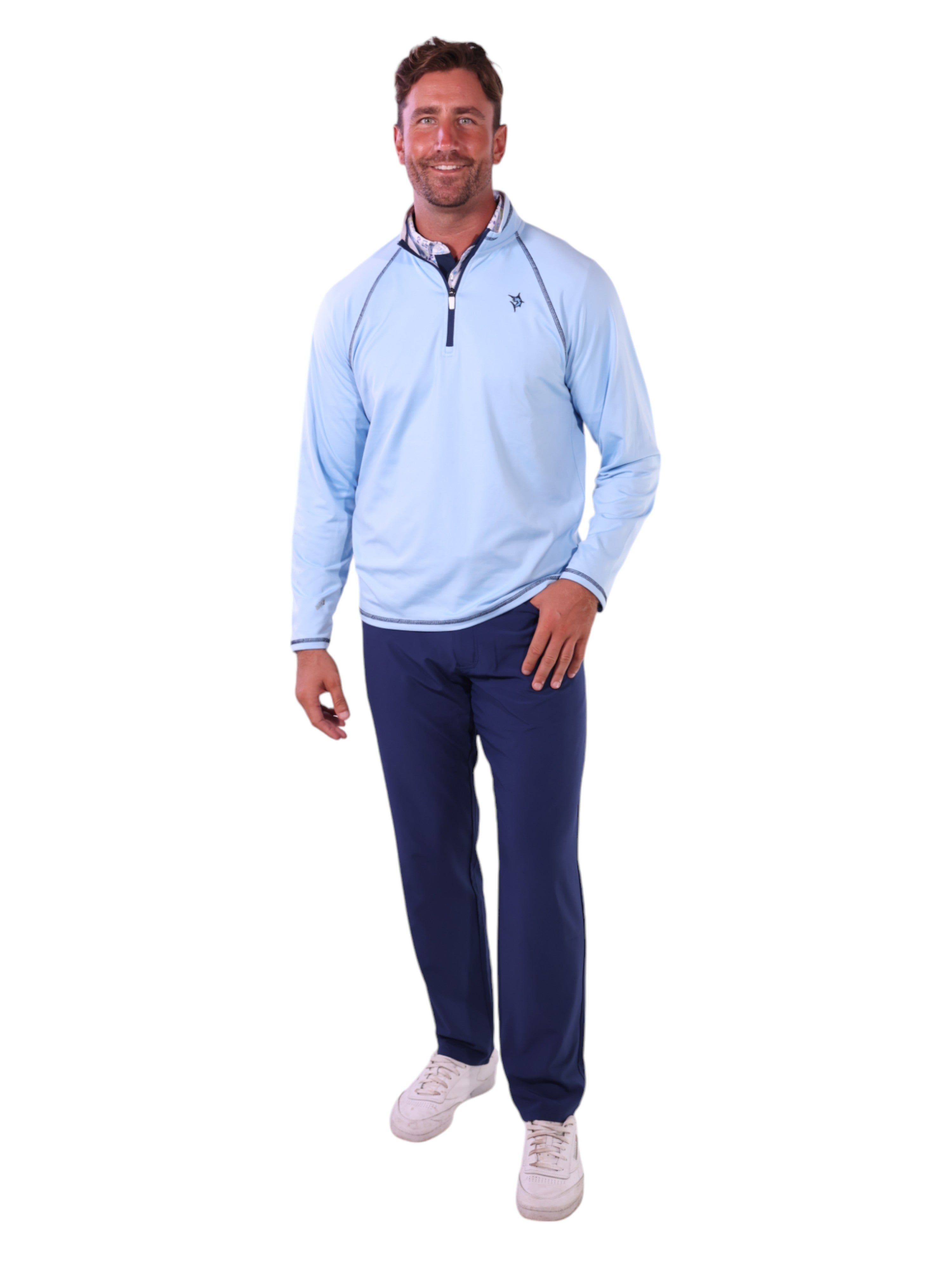 Man wearing a light blue pullover and navy pants on a white background