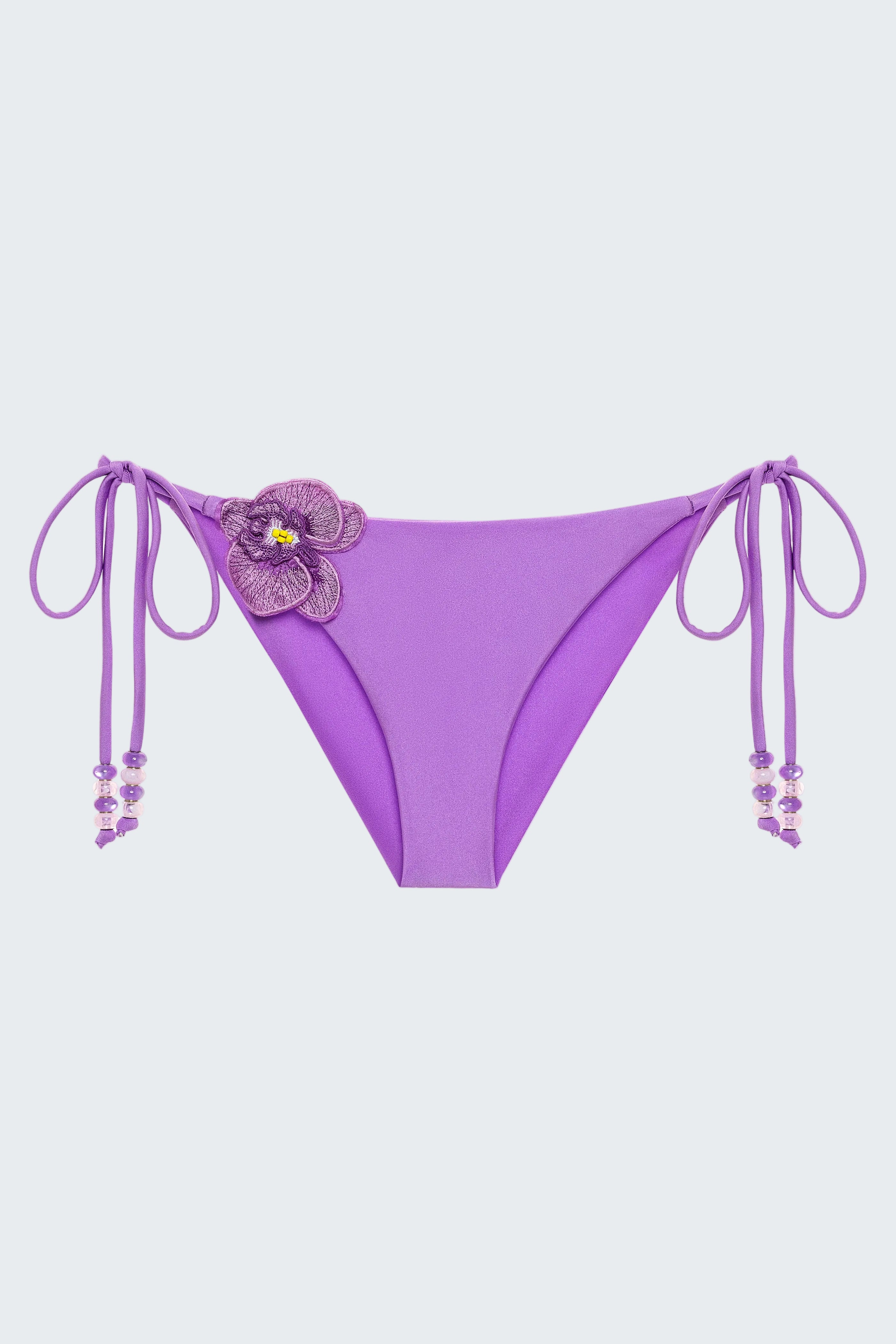 Purple bikini bottom with floral design and string details on a white background