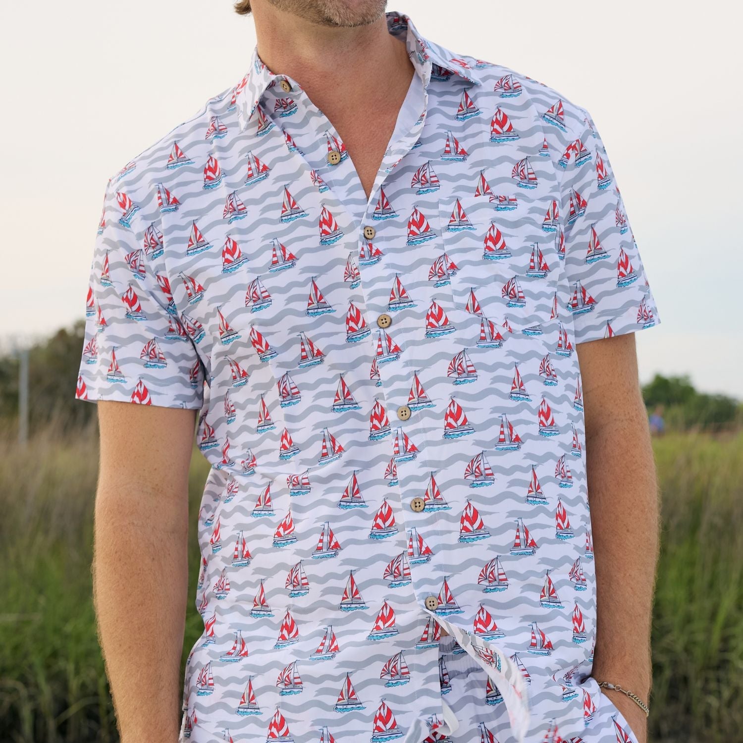 Person wearing a patterned shirt with sailboat design outdoors