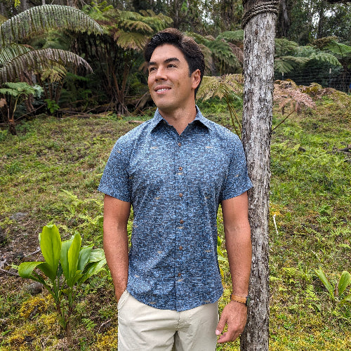 Man standing outdoors in a natural setting with greenery