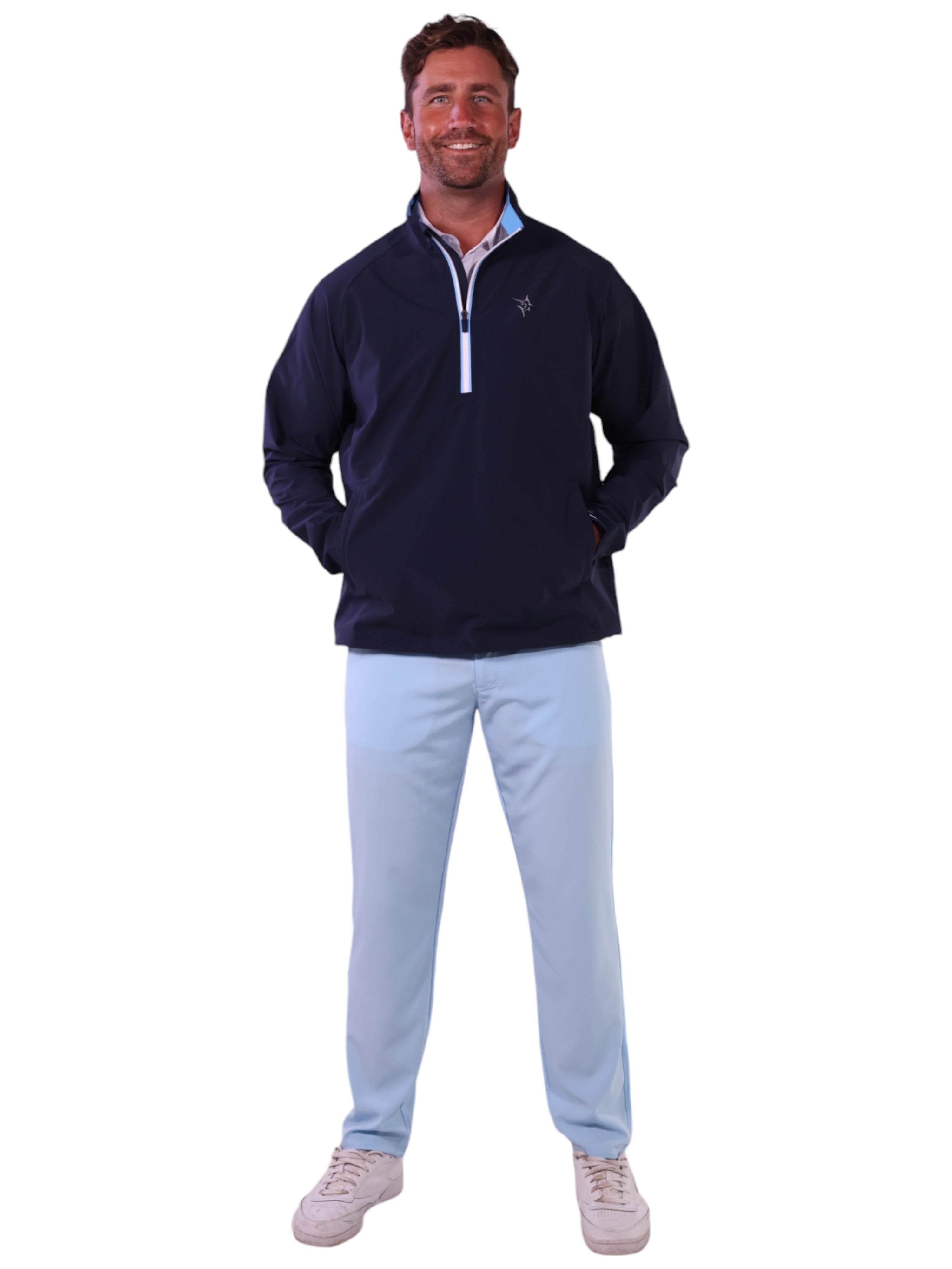 Man wearing a navy pullover with a zipper and light blue pants on a white background