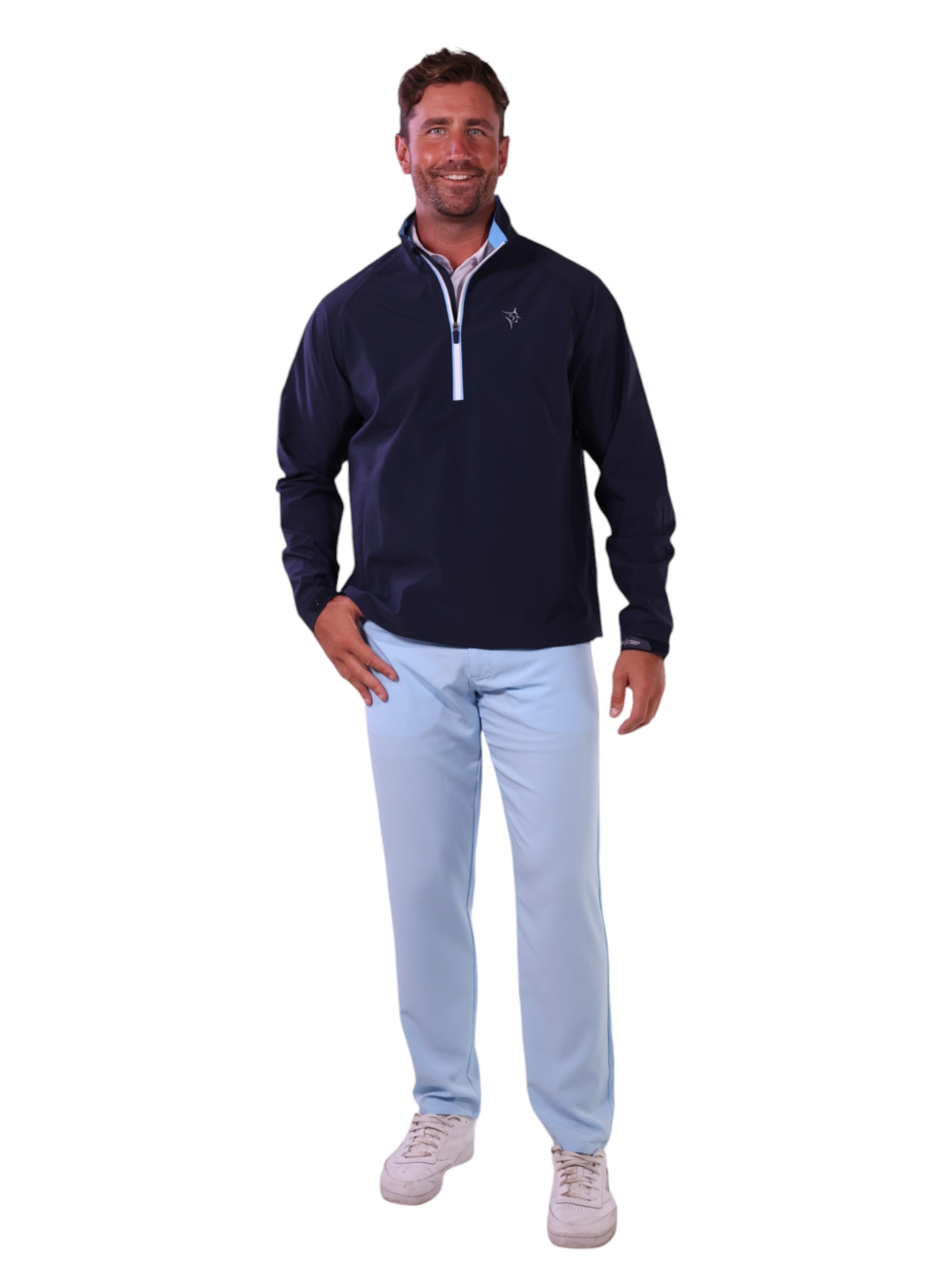 Man wearing a navy pullover with a zipper and light blue pants on a white background