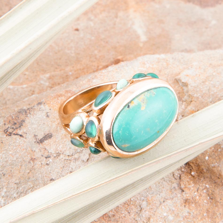 Gold ring with turquoise stones on a textured surface