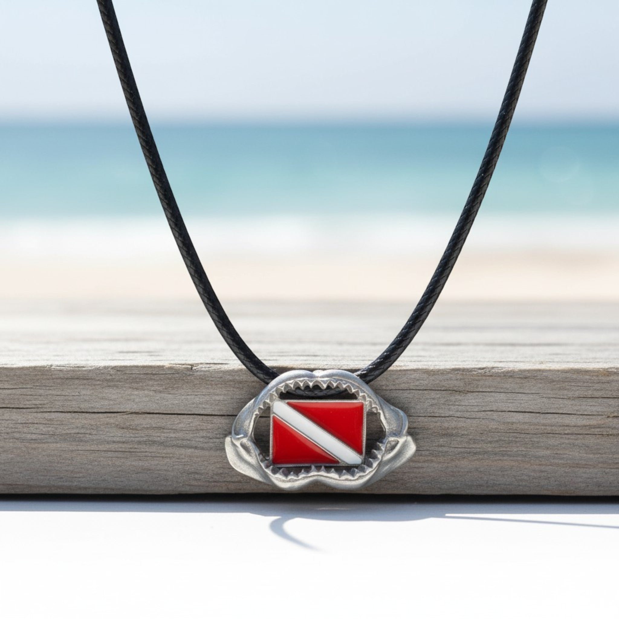 Necklace with a scuba diving flag pendant on a blurred beach background