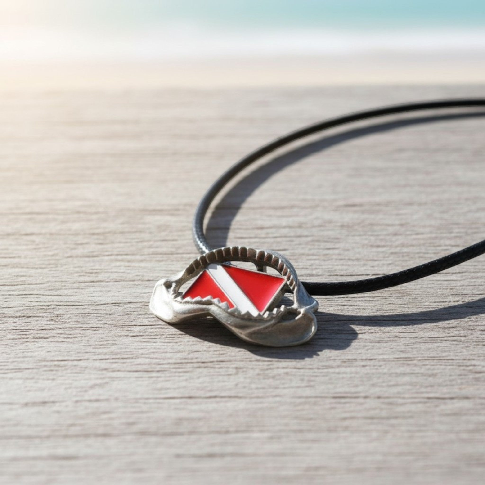 Necklace with a red and white diving flag pendant on a wooden surface