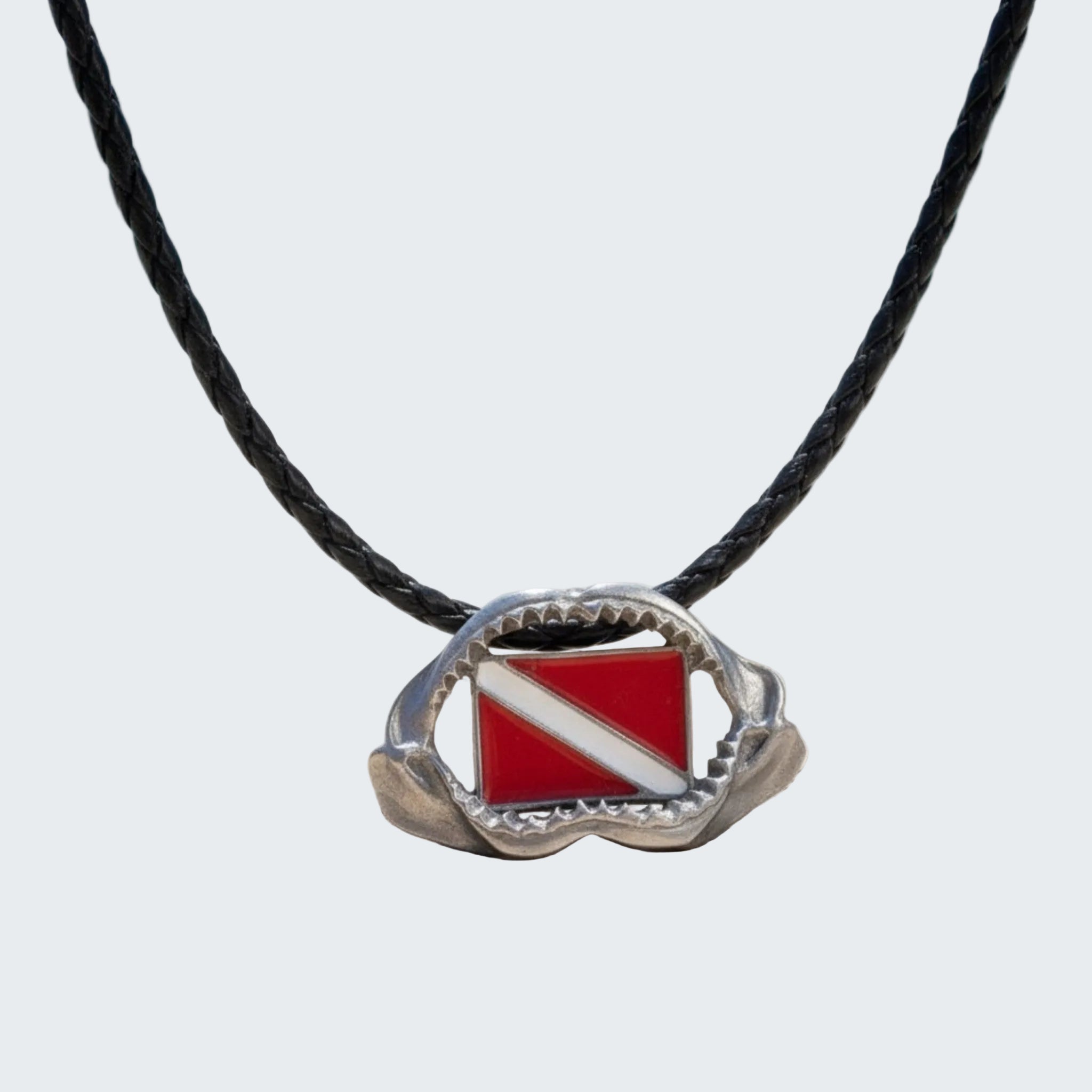 Necklace with a red and white diving flag pendant on a beach background
