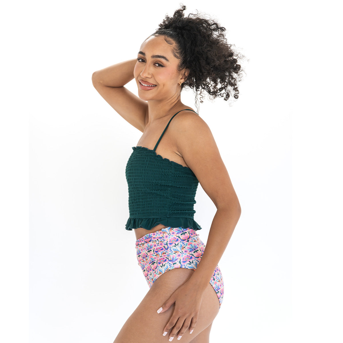 Woman wearing a green top and floral high-waisted shorts on a white background