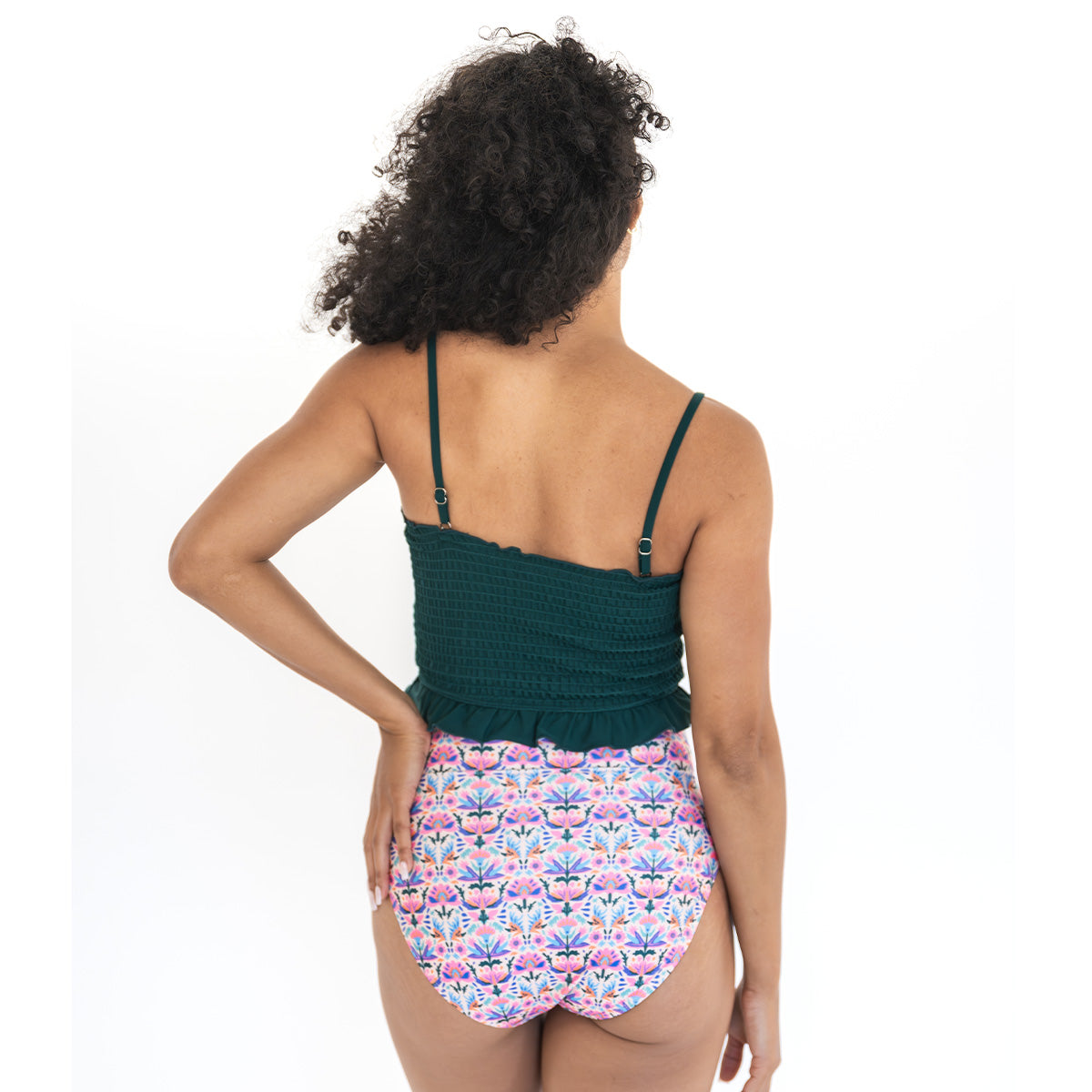 Woman wearing a green top and floral-patterned shorts on a white background