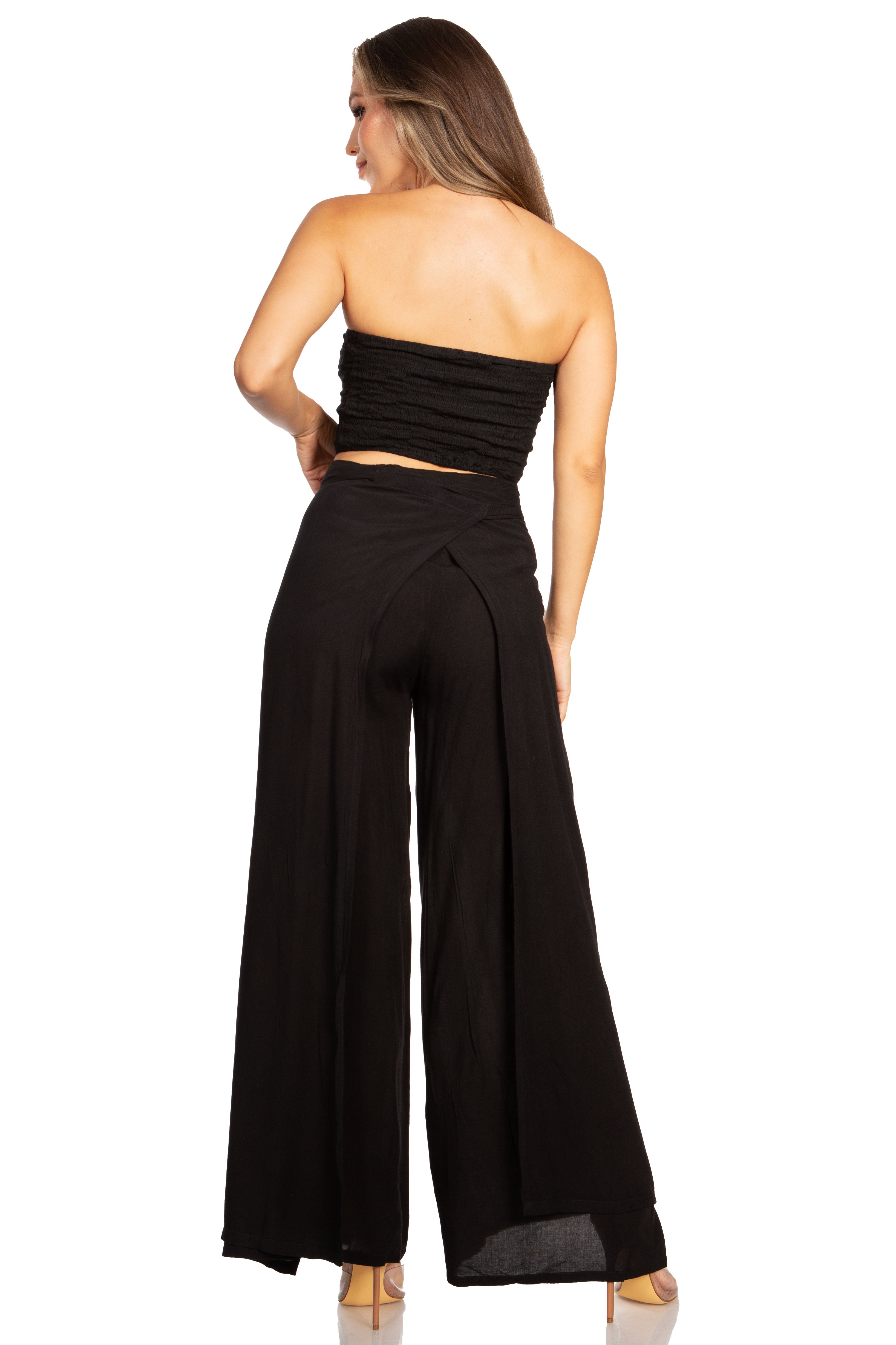 Woman wearing a black strapless top and wide-leg pants on a white background