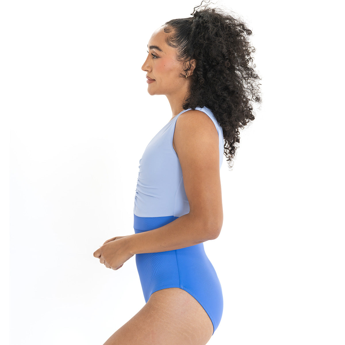 Woman wearing a light blue sleeveless top and blue high-waisted leggings on a white background